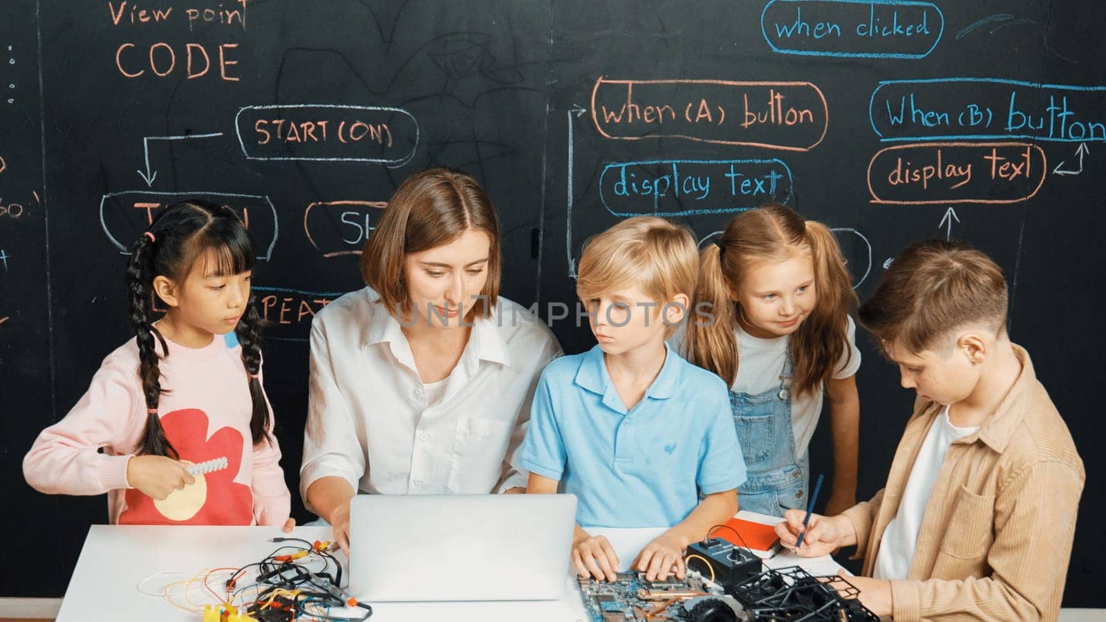 Diverse student writing engineering code while boy fixing mother board. Teacher giving advice and teaching about robotic system while learner studying and learning about coding prompt. Erudition.