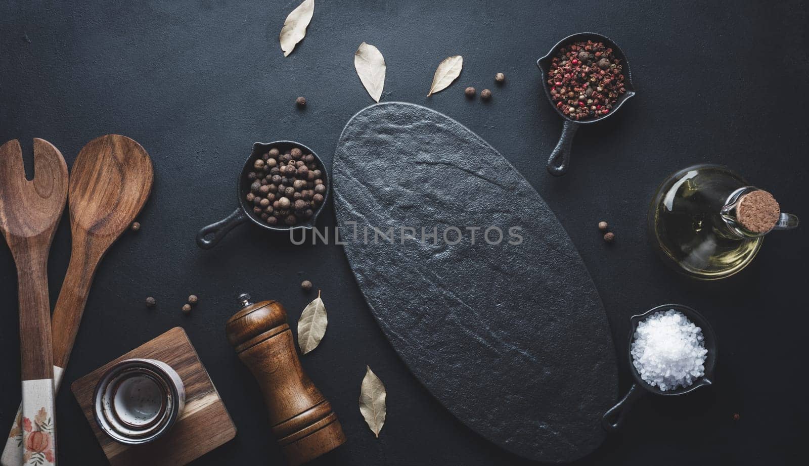 Various spices and an empty black board on the table. Salt, pepper and olive oil, top view