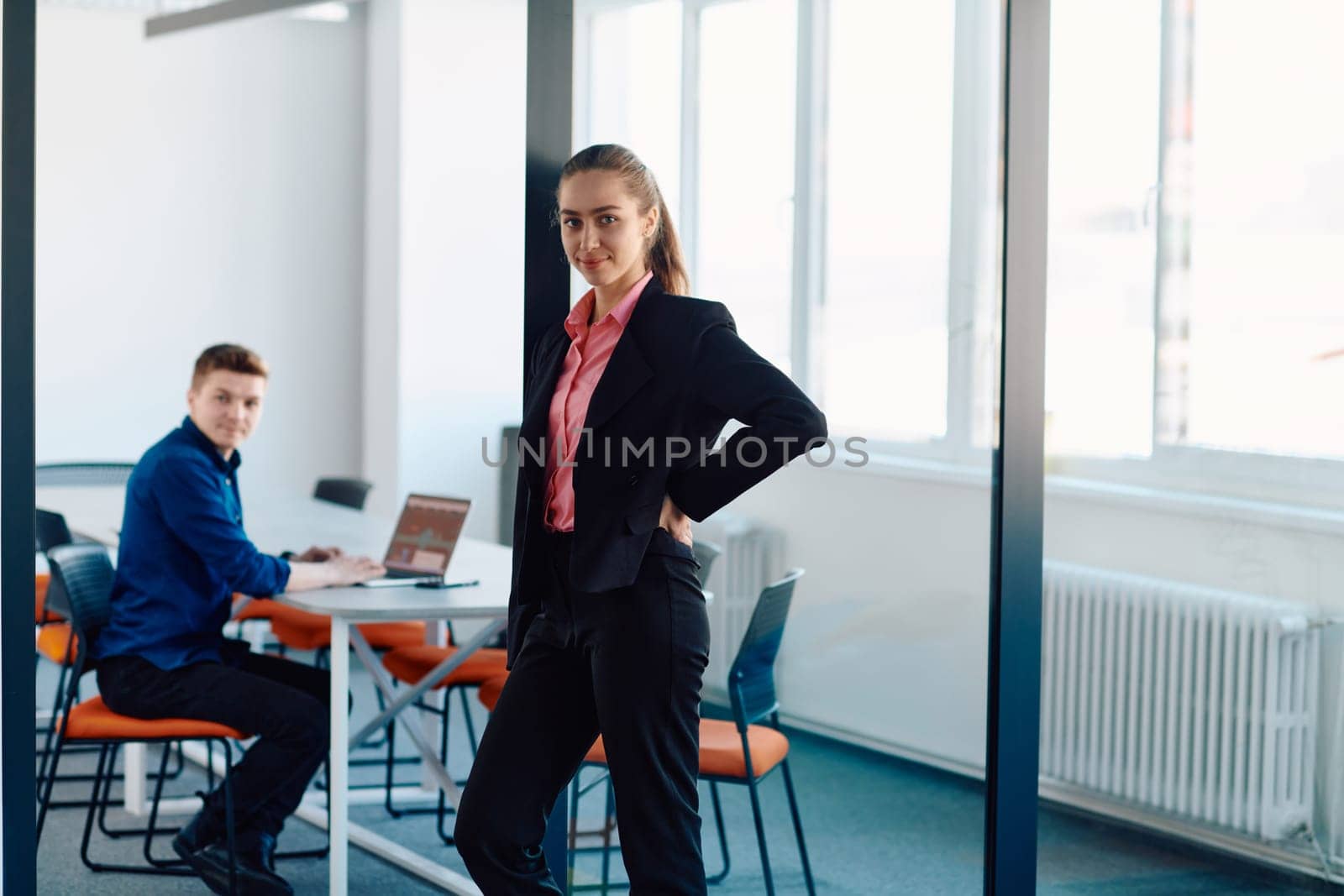The director of an IT company poses with her colleague in a modern startup office setting.