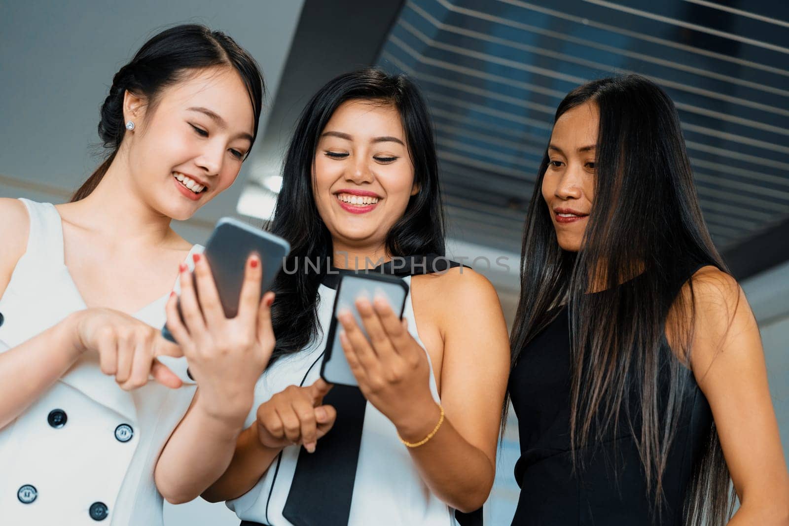 Three women friends having conversation while looking at mobile phone in their hands. Concept of social media, gossip news and online shopping. uds