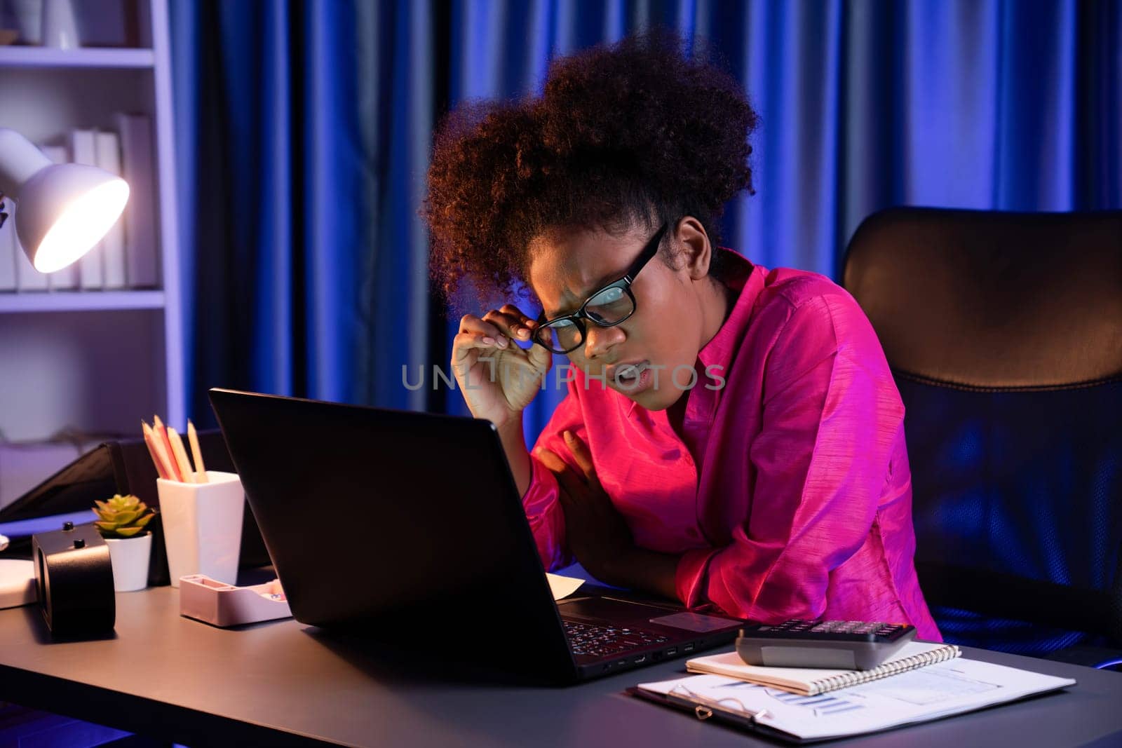 African woman businesswoman or blogger wearing pink shirt with serious face, looking and focusing on screen laptop with struggle project. Concept of stressful expression at work from home. Tastemaker.