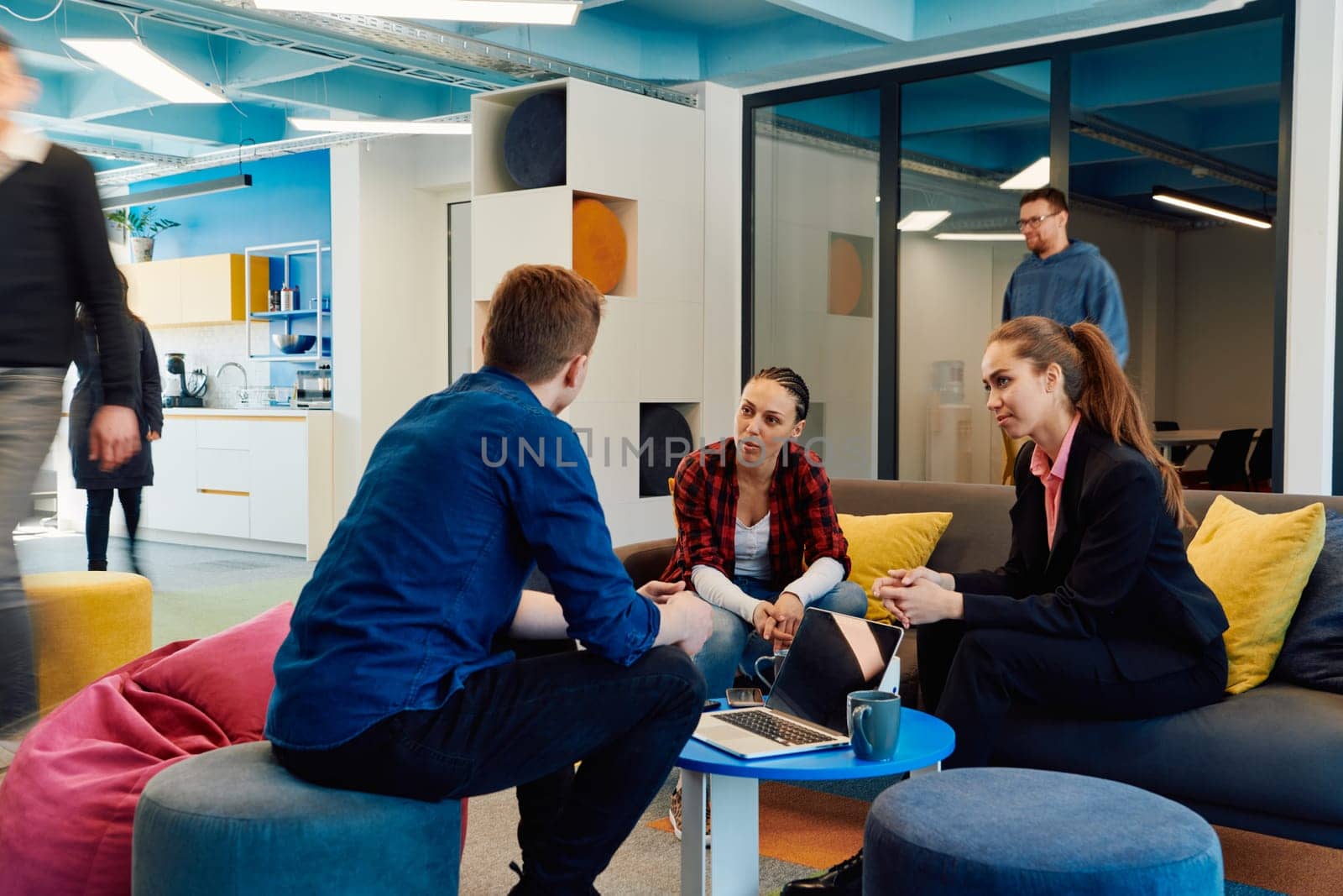 Multiethnic startup business team on meeting in a modern bright open space coworking office. Brainstorming, working on laptop. Group of coworkers walking around in motion blur by dotshock