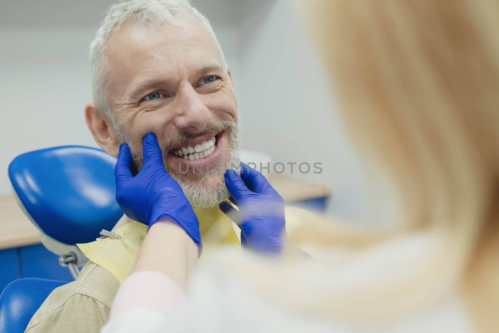 Dental doctor treating a male patient in hospital. by Сookiestock