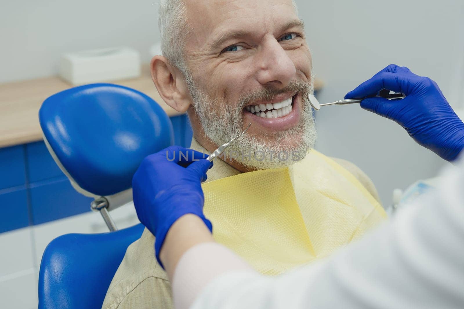 Dental doctor treating a male patient in hospital. by Сookiestock