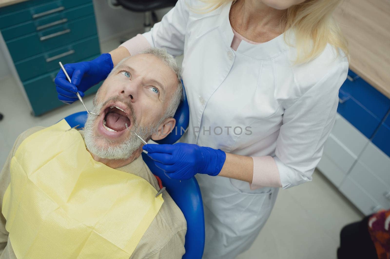 Dental doctor treating a male patient in hospital. by Сookiestock