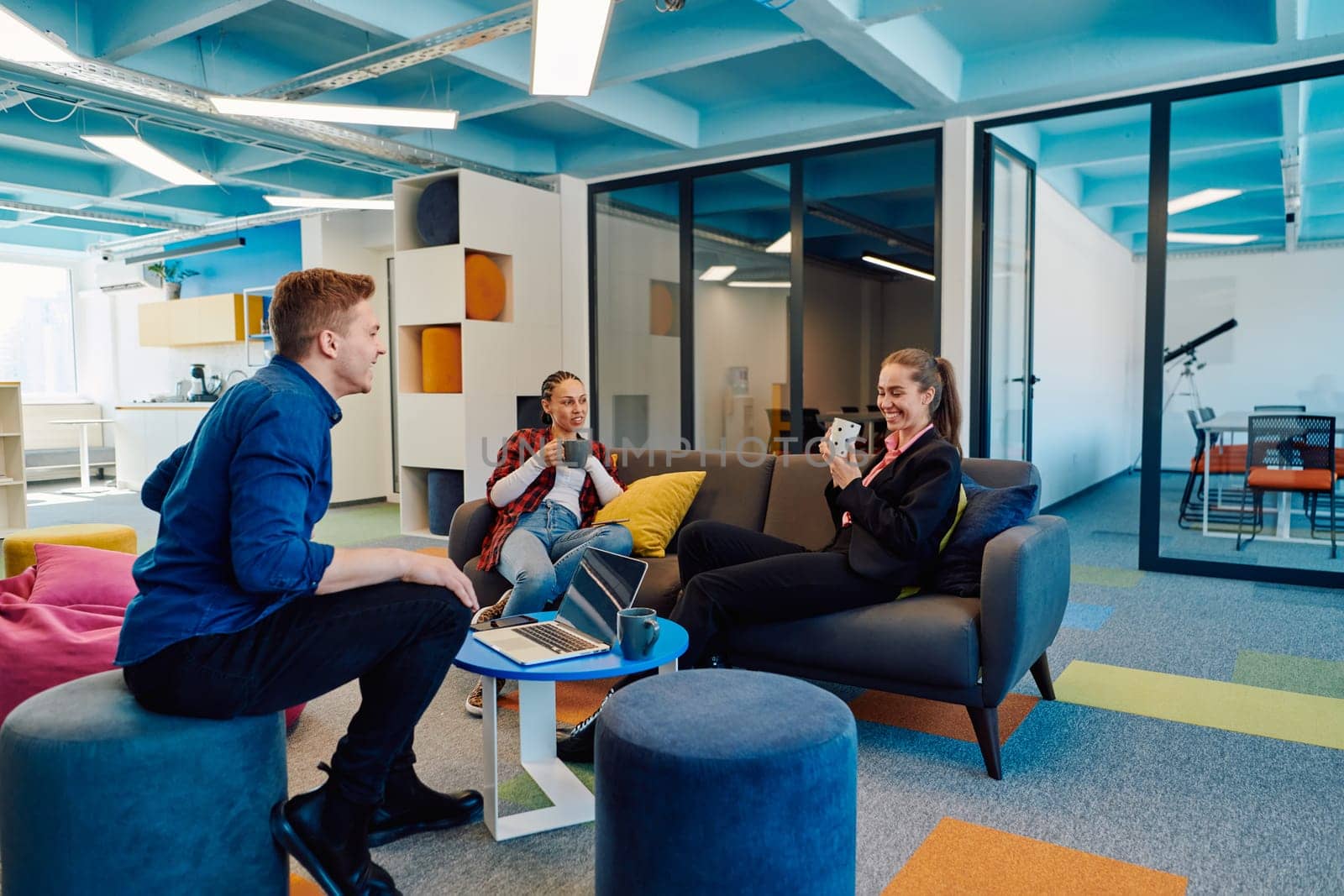 Multiethnic startup business team on meeting in a modern bright open space coworking office. Brainstorming, working on laptop. Group of coworkers walking around in motion blur.