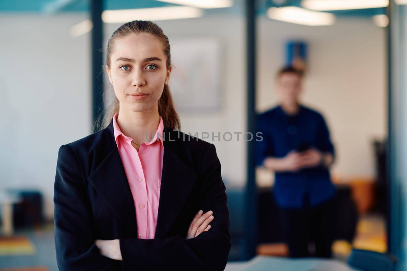 Portrait of a business woman in a creative open space coworking startup office with crossed arms. Successful businesswoman standing in office with copyspace. Associates work in the background by dotshock