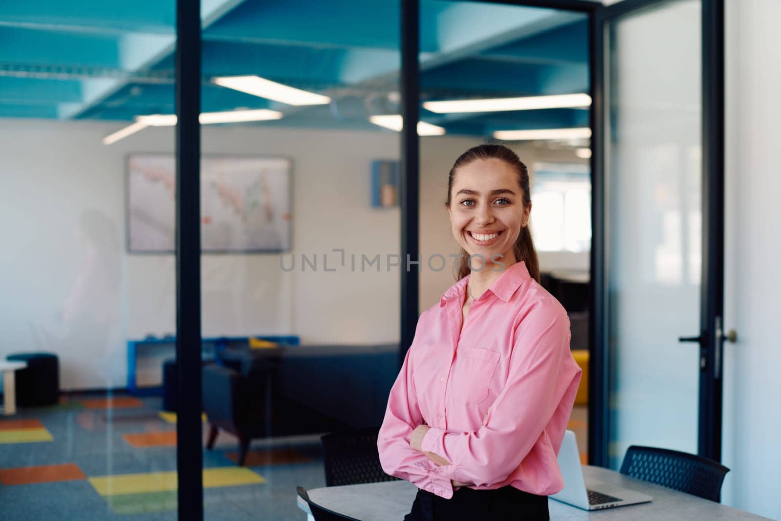 Portrait of a business woman in a creative open space coworking startup office with crossed arms. Successful businesswoman standing in office with copyspace. Associates work in the background.