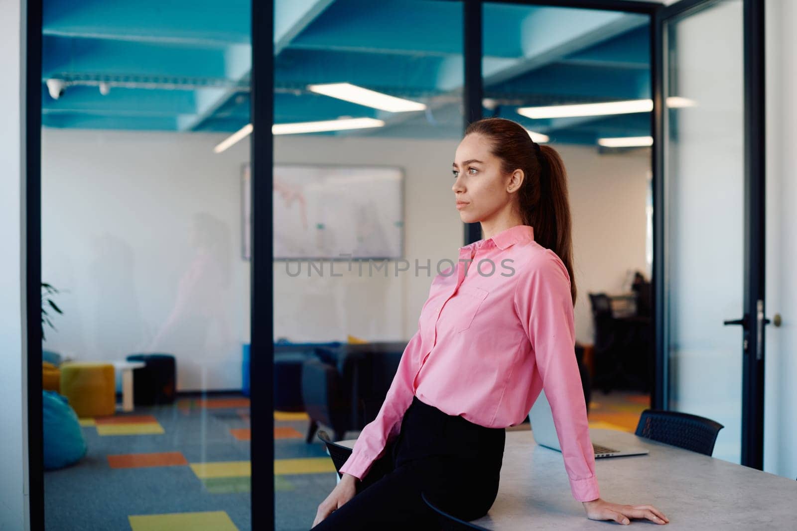 Portrait of young smiling business woman in creative open space coworking startup office. Successful businesswoman standing in office with copyspace. Coworkers working in background.