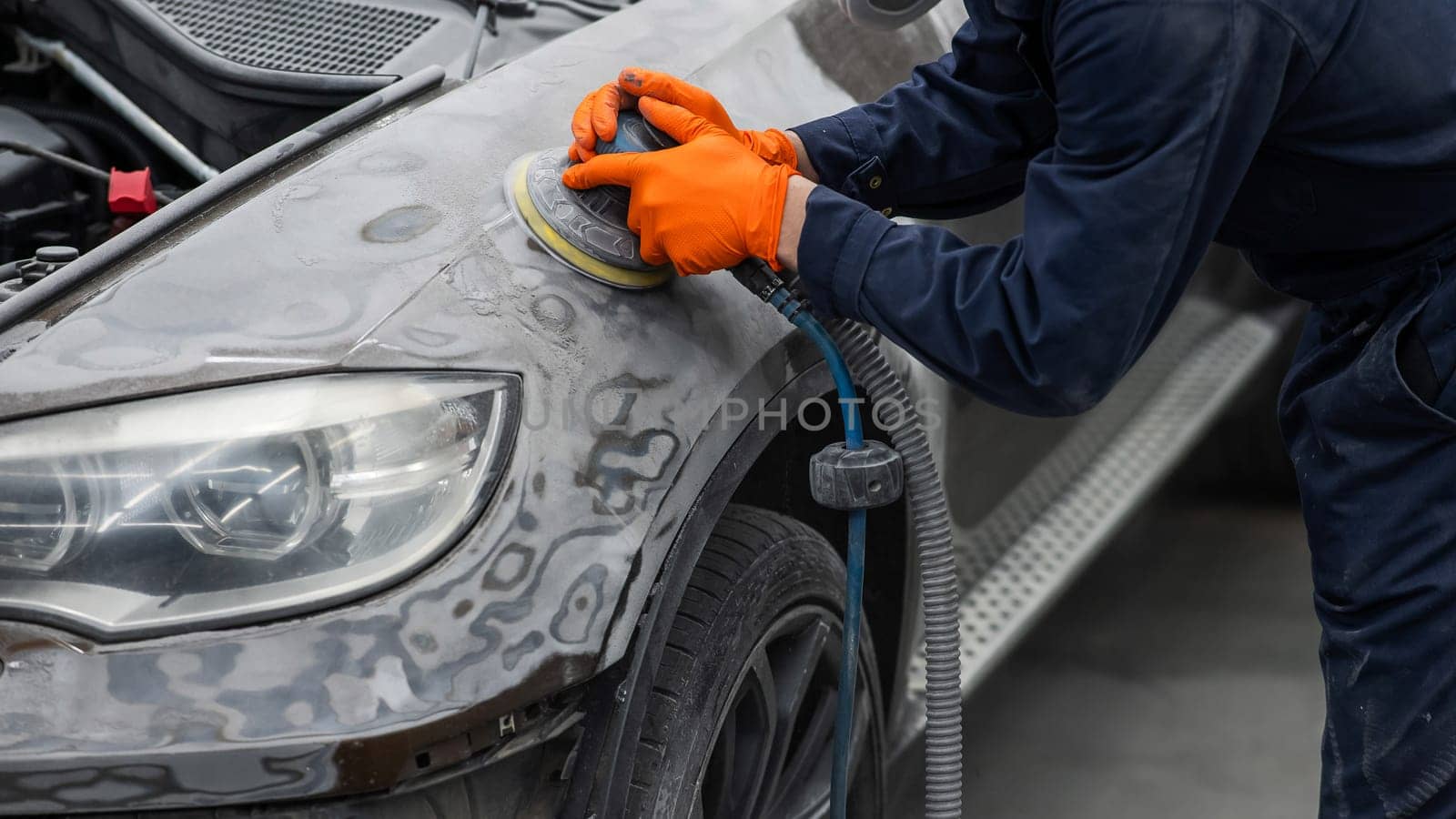 A mechanic sands the putty on a car body with a machine. Repair after an accident. by mrwed54