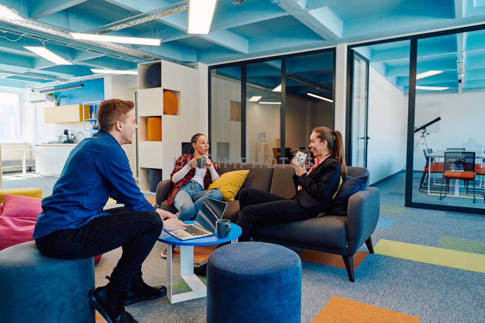 Multiethnic startup business team on meeting in a modern bright open space coworking office. Brainstorming, working on laptop. Group of coworkers walking around in motion blur.