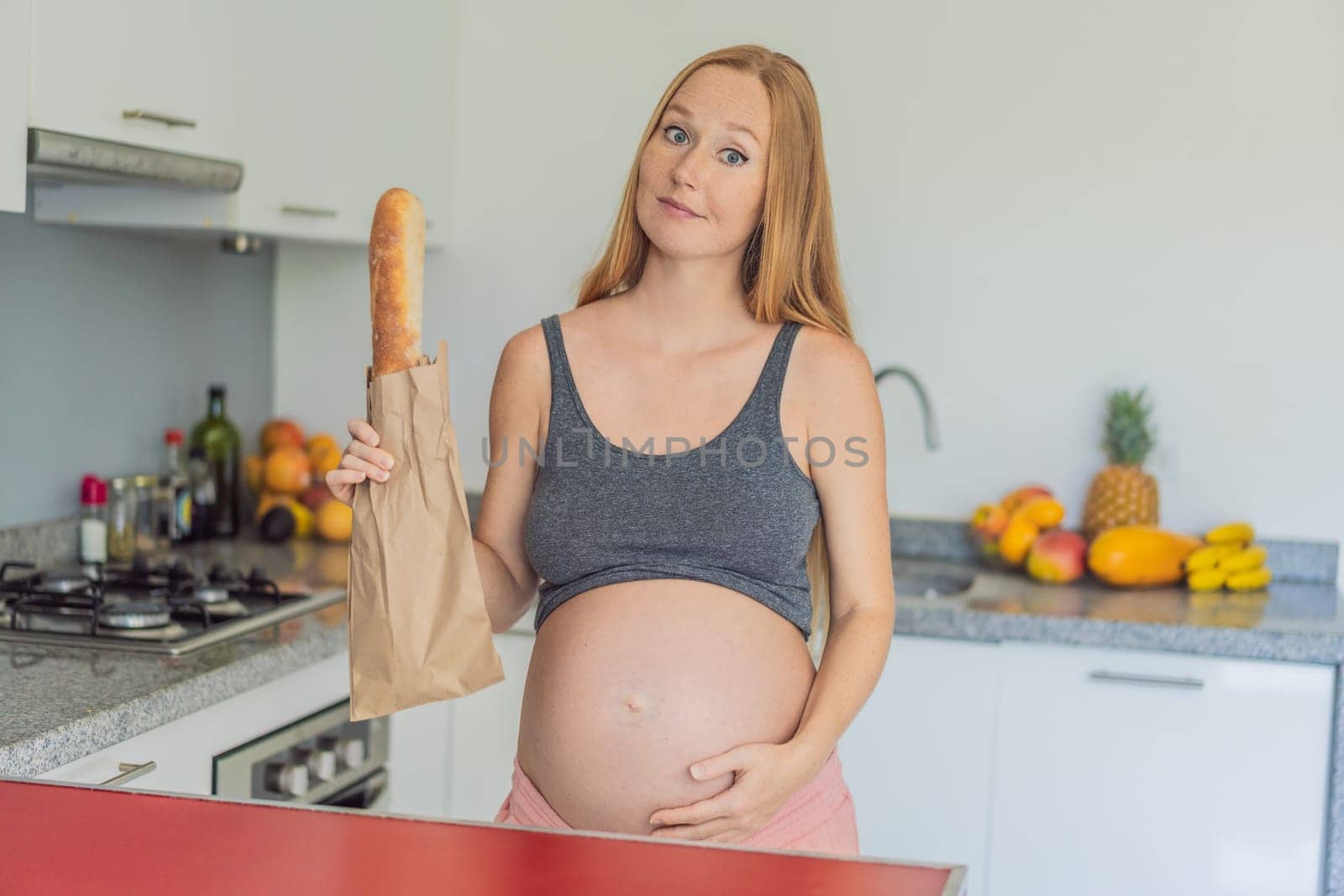 Pregnant woman eating bread in the kitchen. Exploring the impact of gluten during pregnancy: understanding the potential benefits and risks for maternal health and fetal development by galitskaya