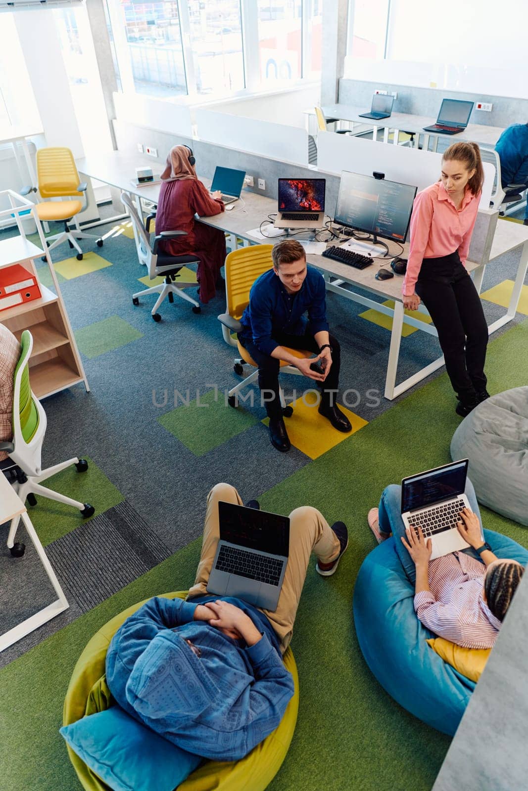 In a modern startup office, a diverse group of young and capable businesspeople engage in lively discussions about various projects, showcasing teamwork, innovation, and entrepreneurial spirit.