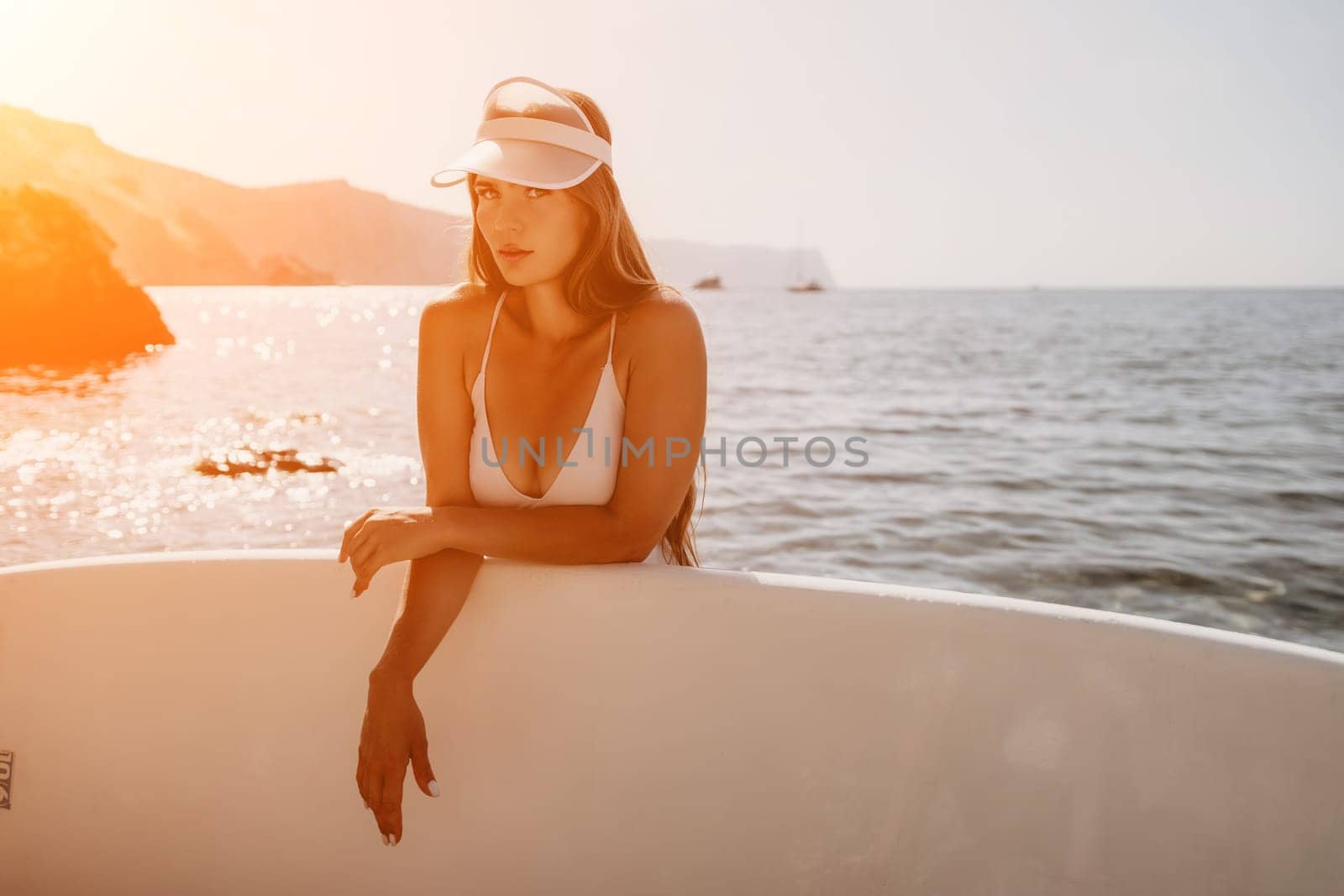 Close up shot of happy young caucasian woman looking at camera and smiling. Cute woman portrait in bikini posing on a volcanic rock high above the sea