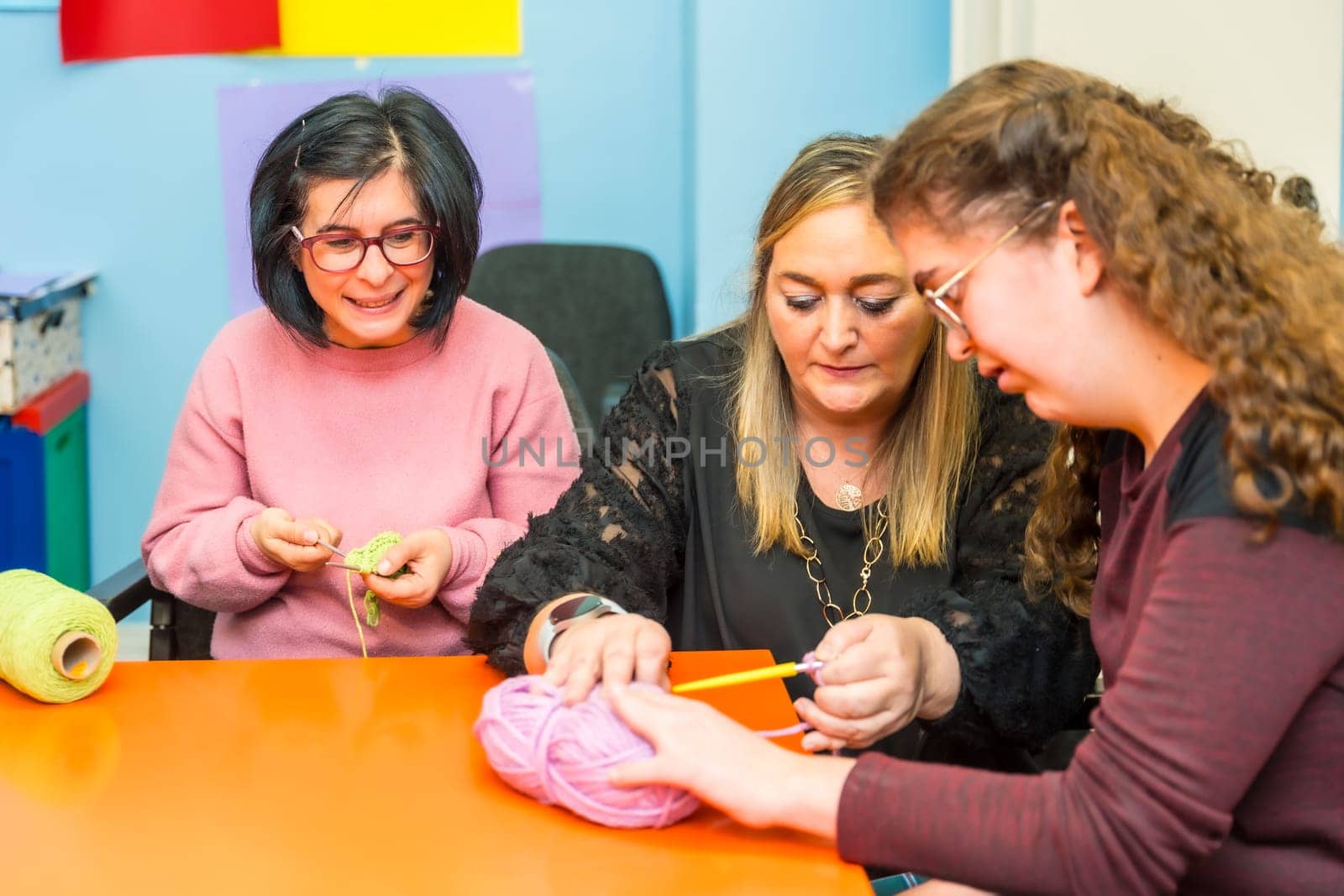 Women with intellectual disabilities and teacher knitting clothes with wool by Huizi