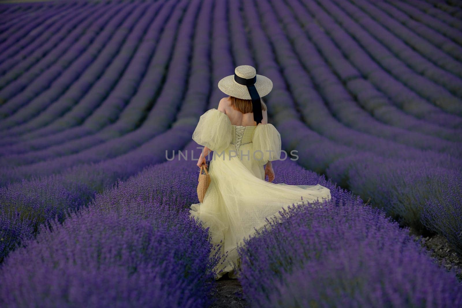 Back view woman lavender sunset. Happy woman in yellow dress holds lavender bouquet. Aromatherapy concept, lavender oil, photo session in lavender by Matiunina