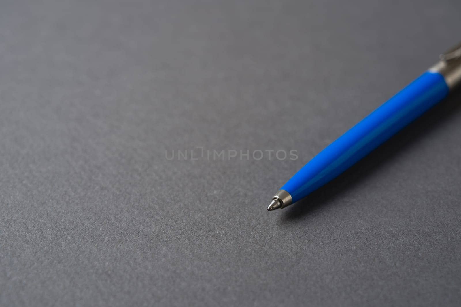 Blue plastic and metal ballpoint pen on dark gray background
