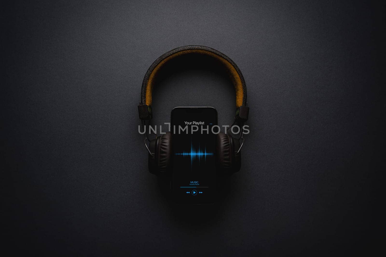 Smartphone with music player app and on-ear headphones on dark gray background by Sonat