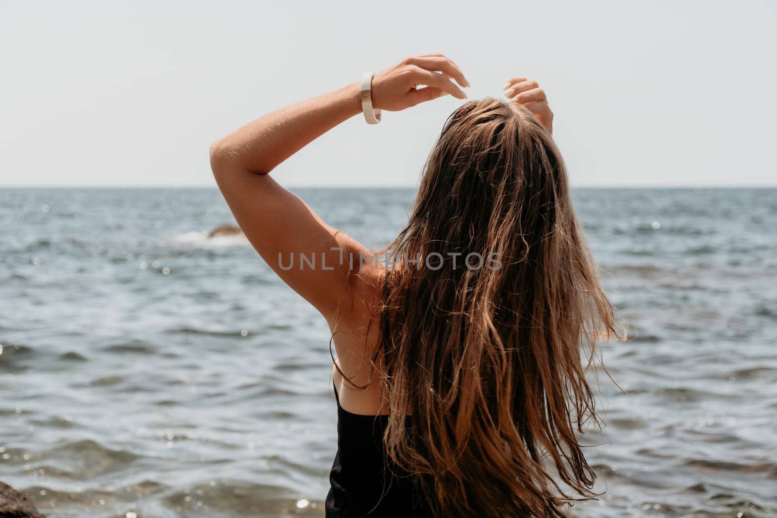 Woman travel sea. Young Happy woman in a long red dress posing on a beach near the sea on background of volcanic rocks, like in Iceland, sharing travel adventure journey