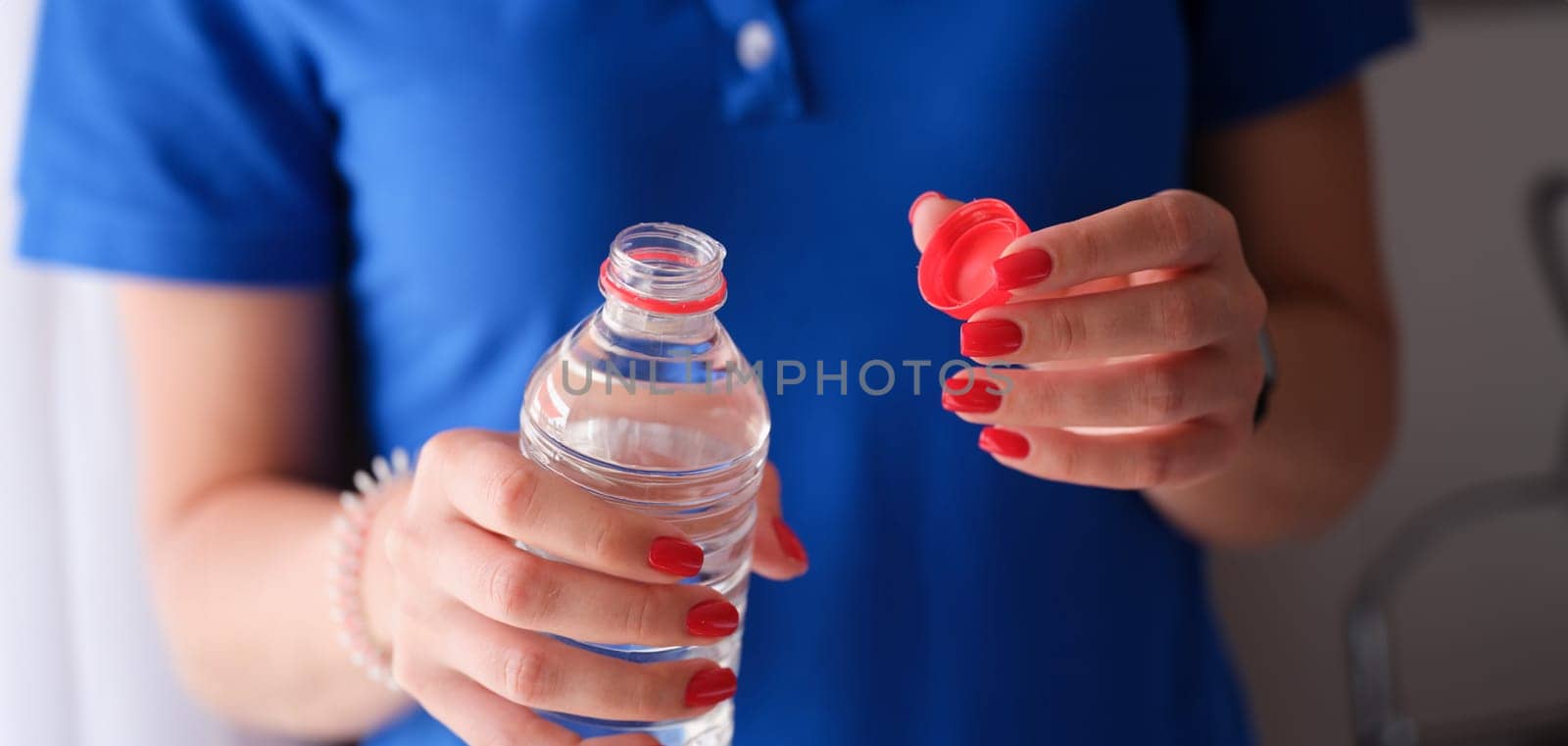 Woman opening plastic bottle with clean water. by kuprevich