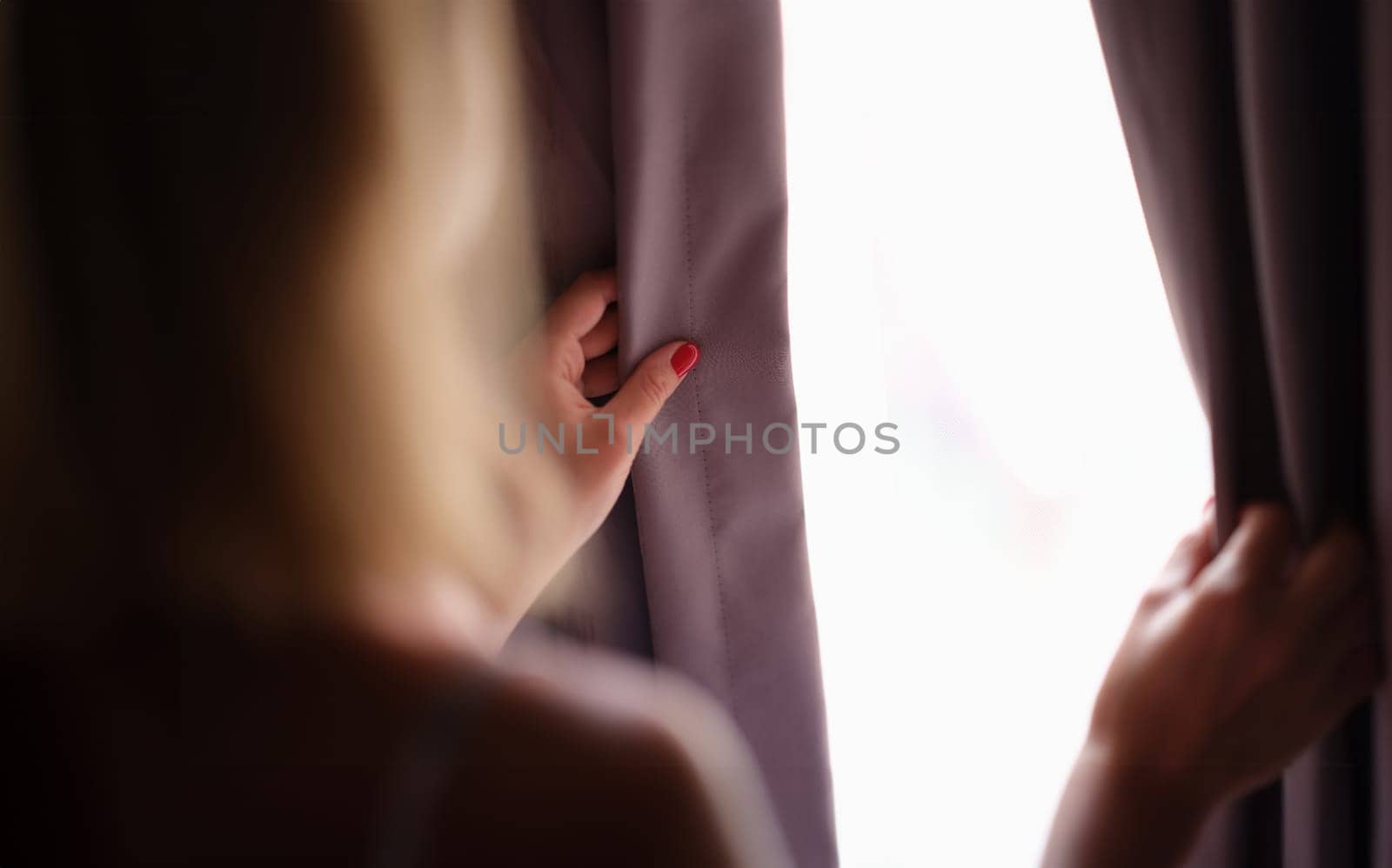 Woman opens curtains at home in morning closeup by kuprevich