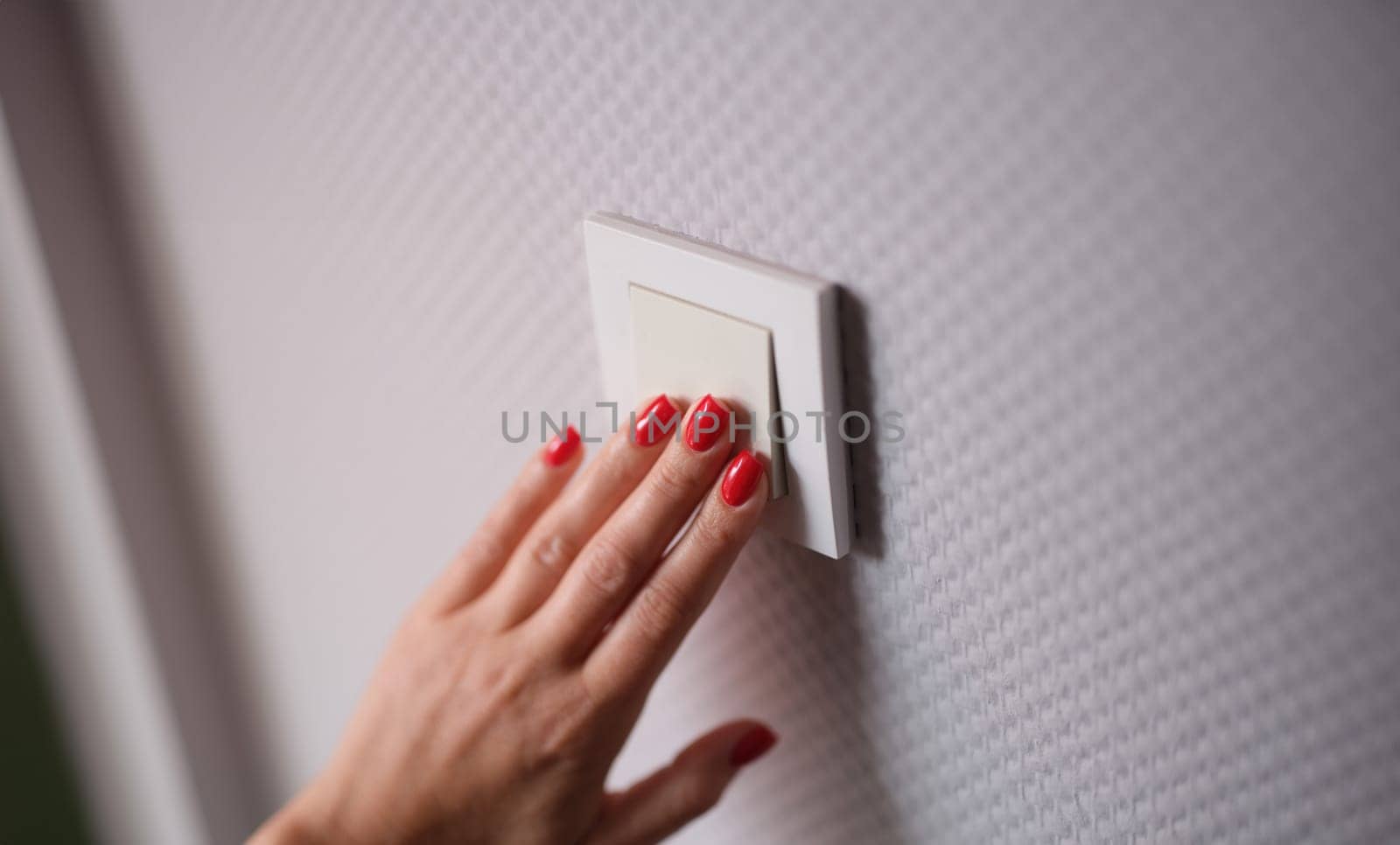 Female hand presses white switch on gray wall closeup by kuprevich