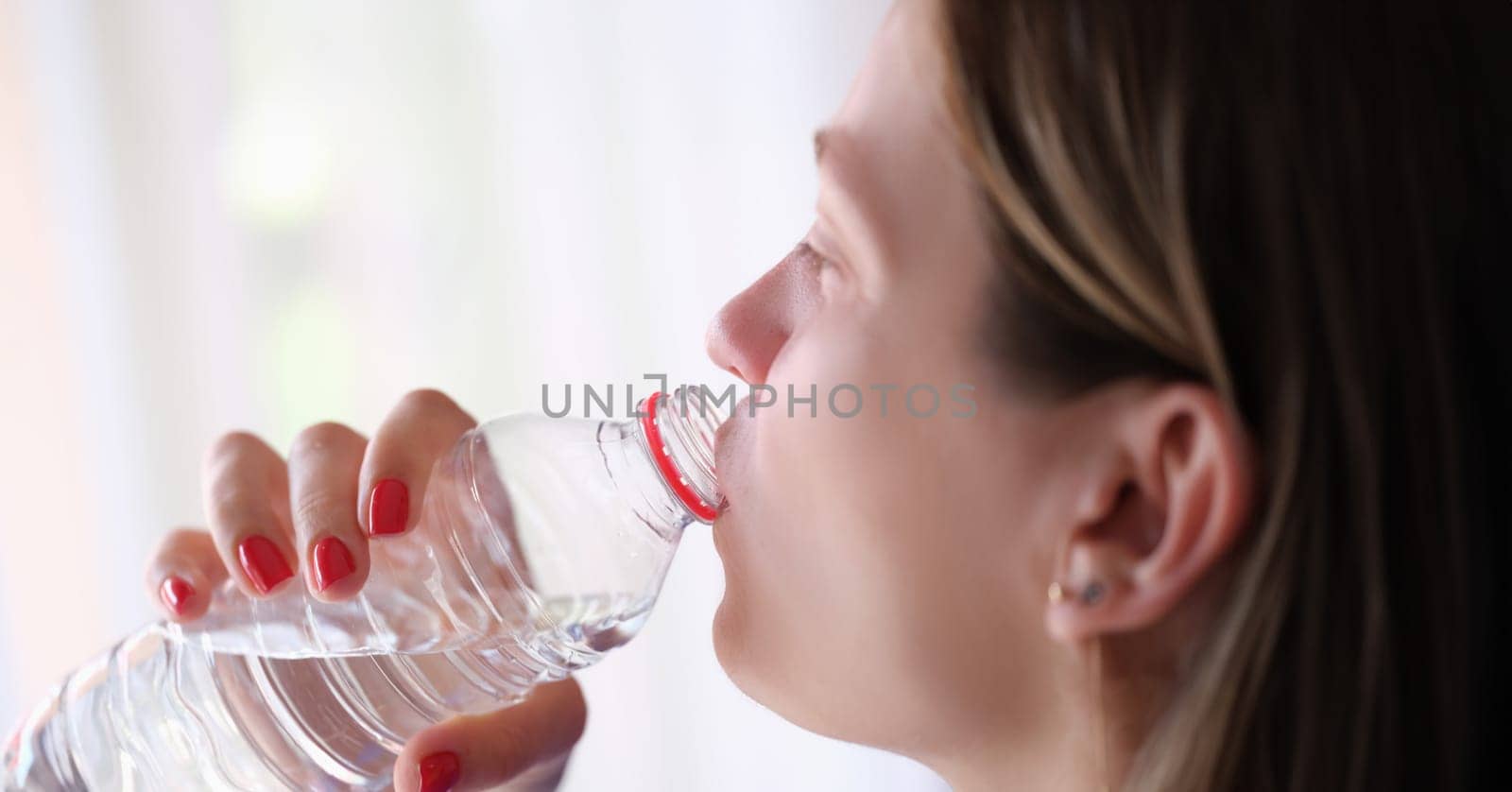 Young woman drinks water from bottle closeup by kuprevich