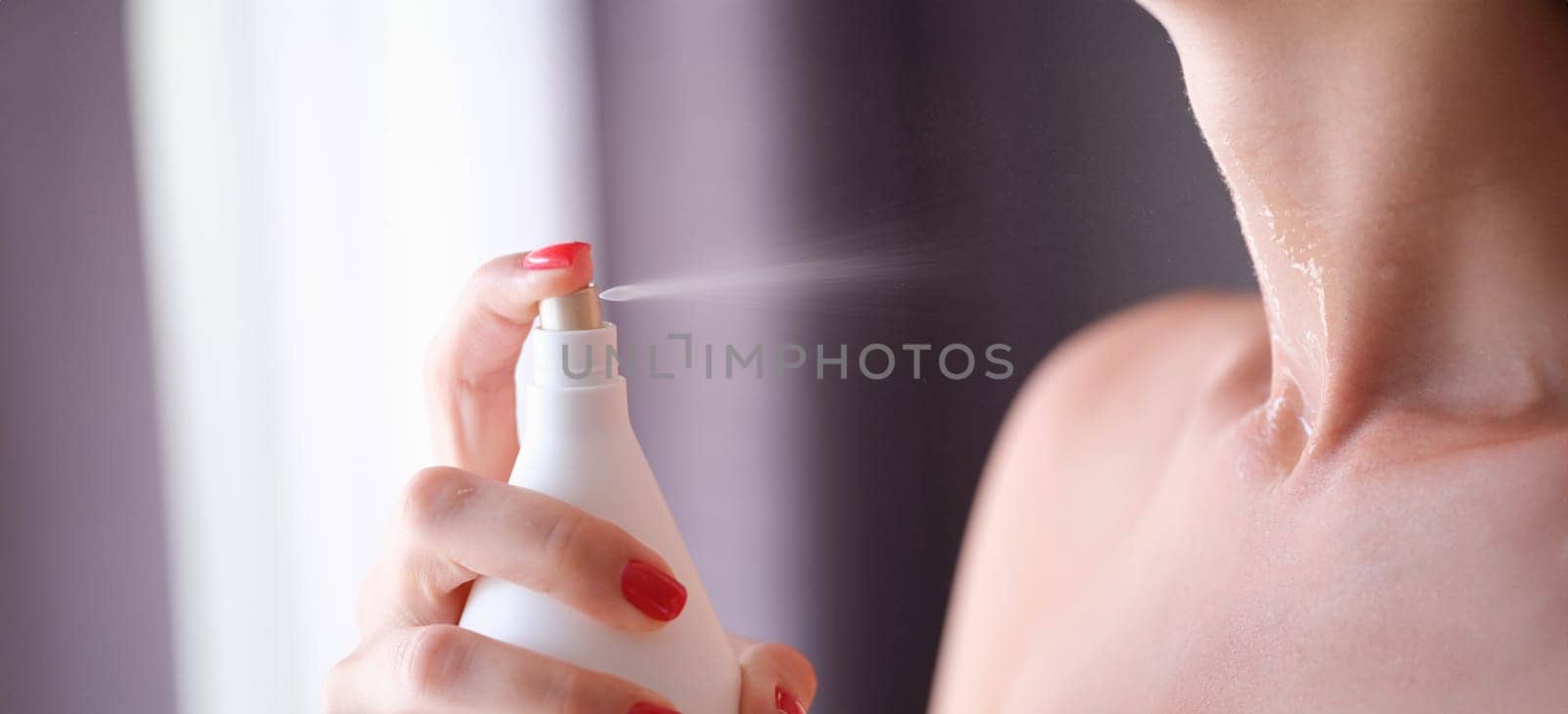 Woman spraying perfume or moisturizing skin lotion on neck closeup. Neck care concept