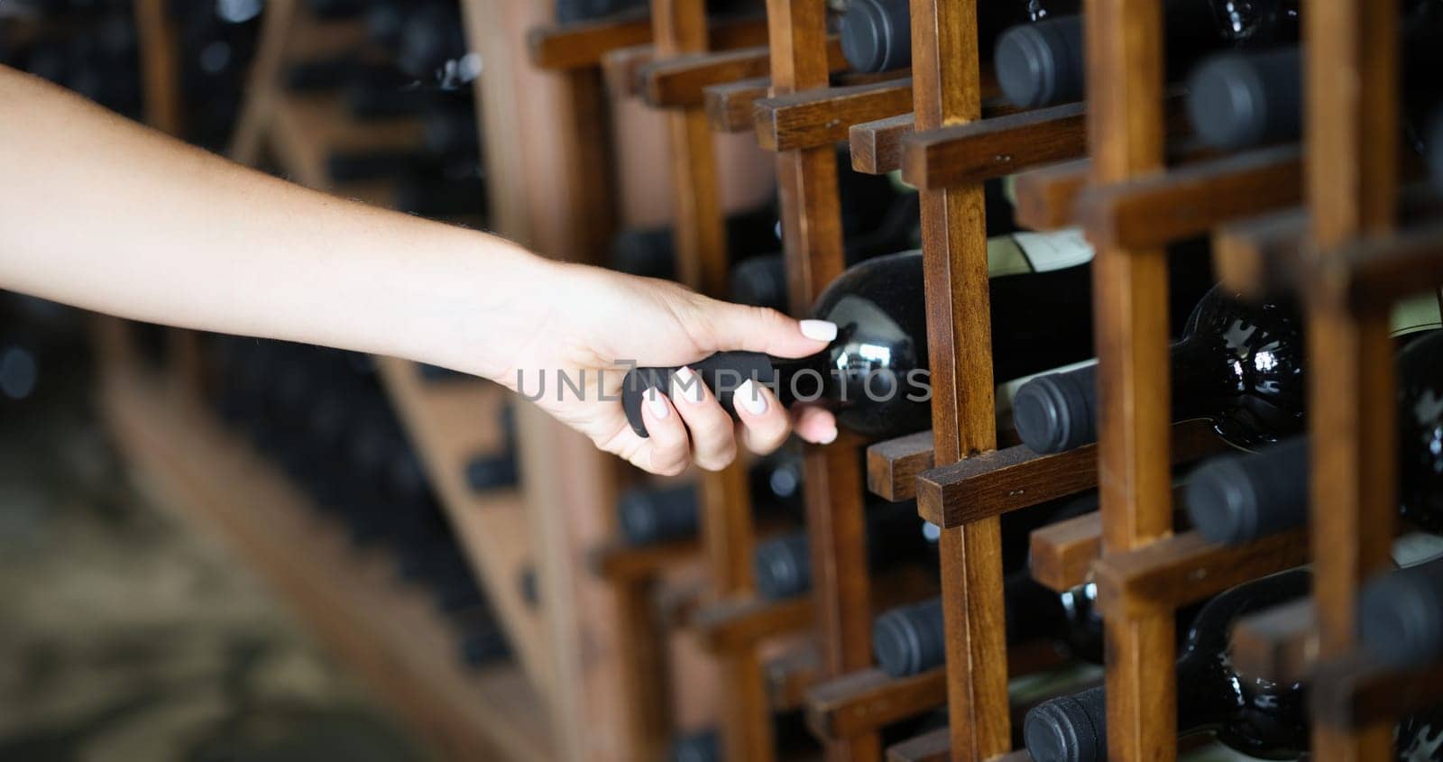 Bartender taking bottle of wine from shelf in basement. Wine tasting from wine tasting club concept