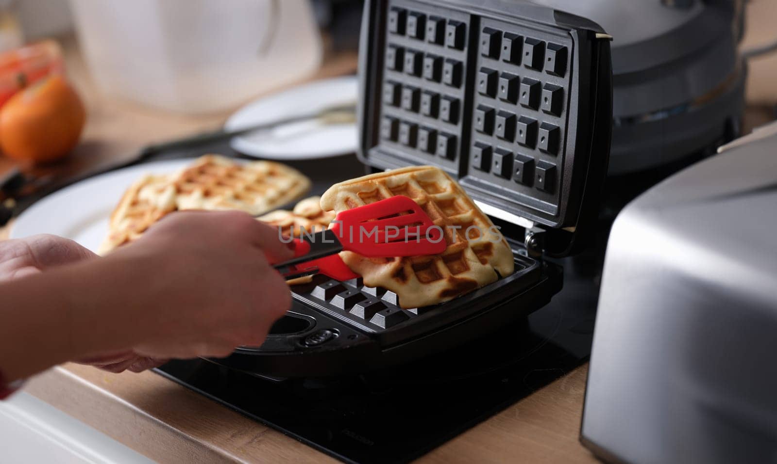 Belgian waffles in waffle iron in kitchen. hef pulls finished Belgian waffles out of oven concept