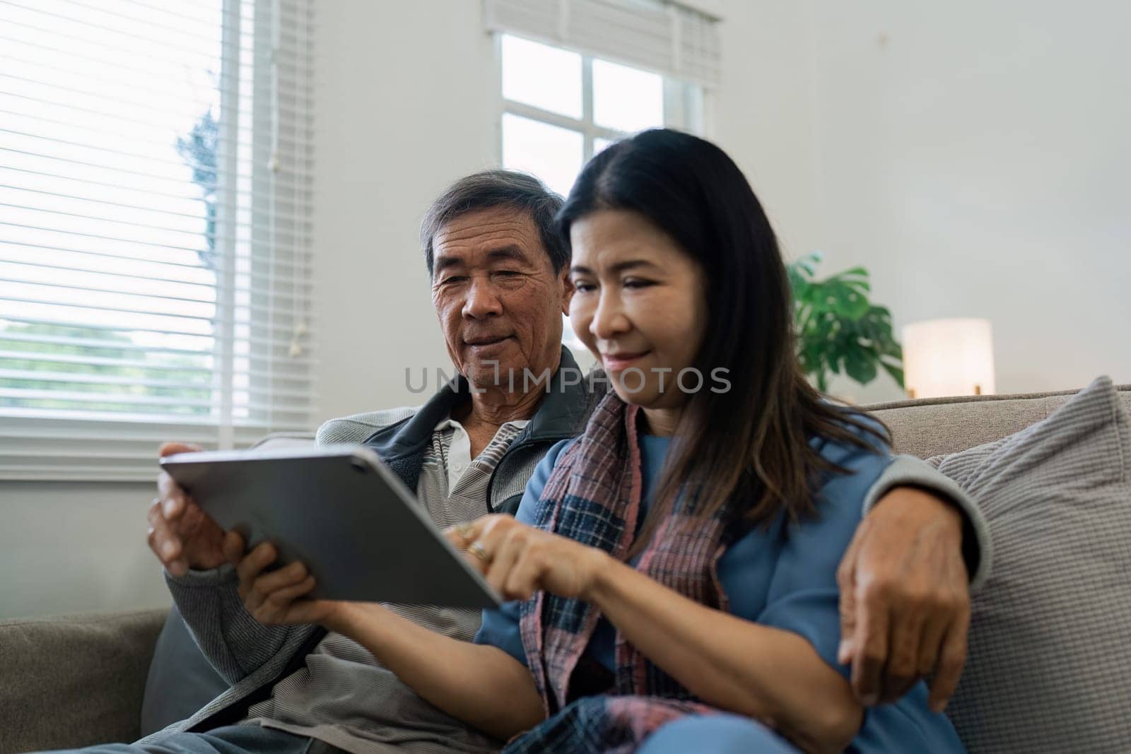Smiling caucasian senior elderly couple grandparent using tablet together.