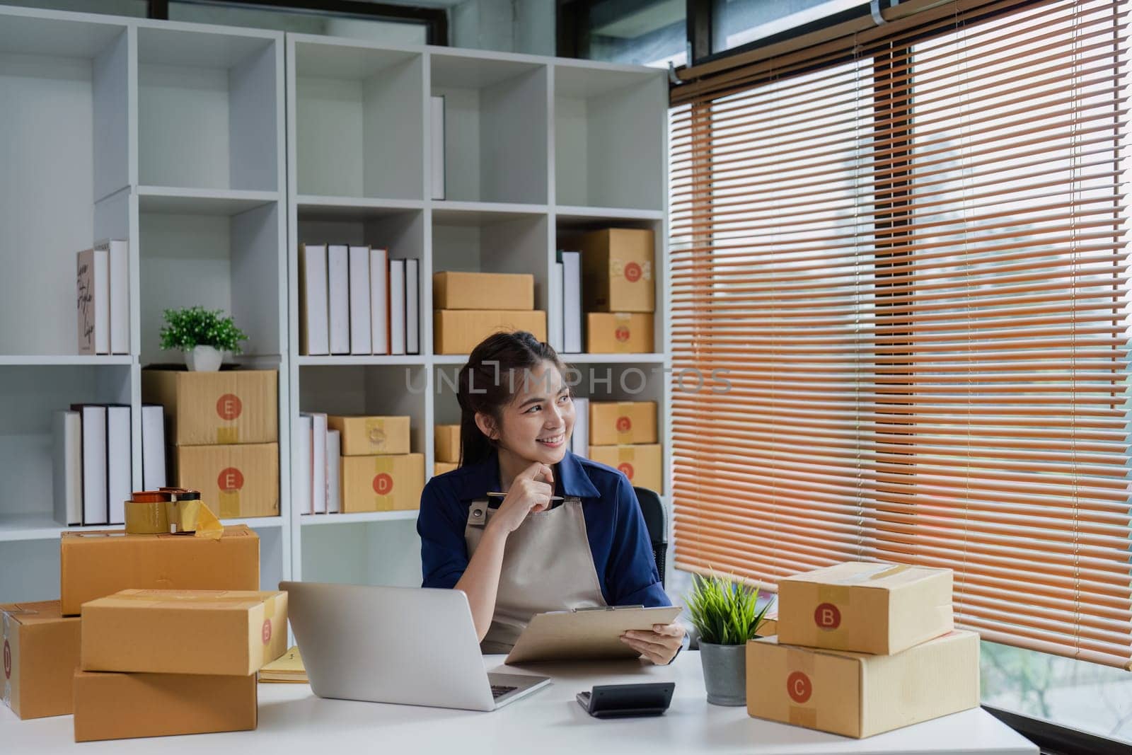 Startup small business entrepreneur woman using a laptop for prepare package with box to client by itchaznong