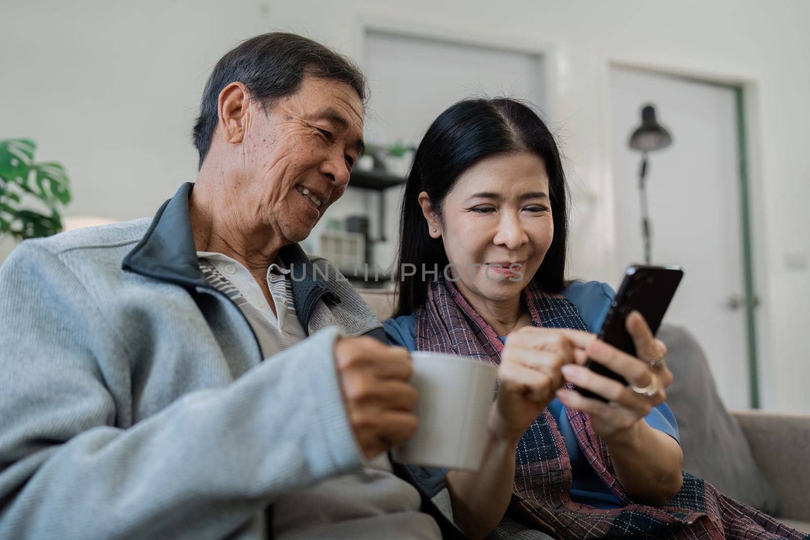 Smiling caucasian senior elderly couple grandparent using mobile together.
