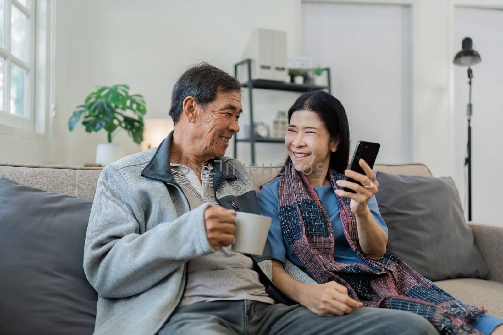 Smiling caucasian senior elderly couple grandparent using mobile together by itchaznong