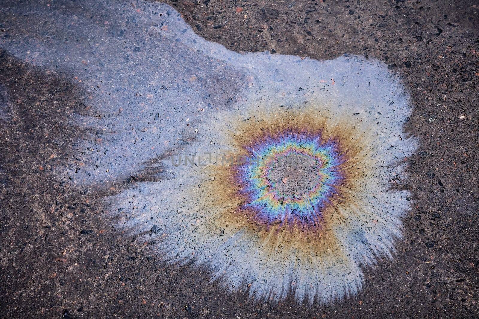 Oil spill on asphalt in the form of a stain. Abstract background from motor oil, gas or petrol spilled on asphalt