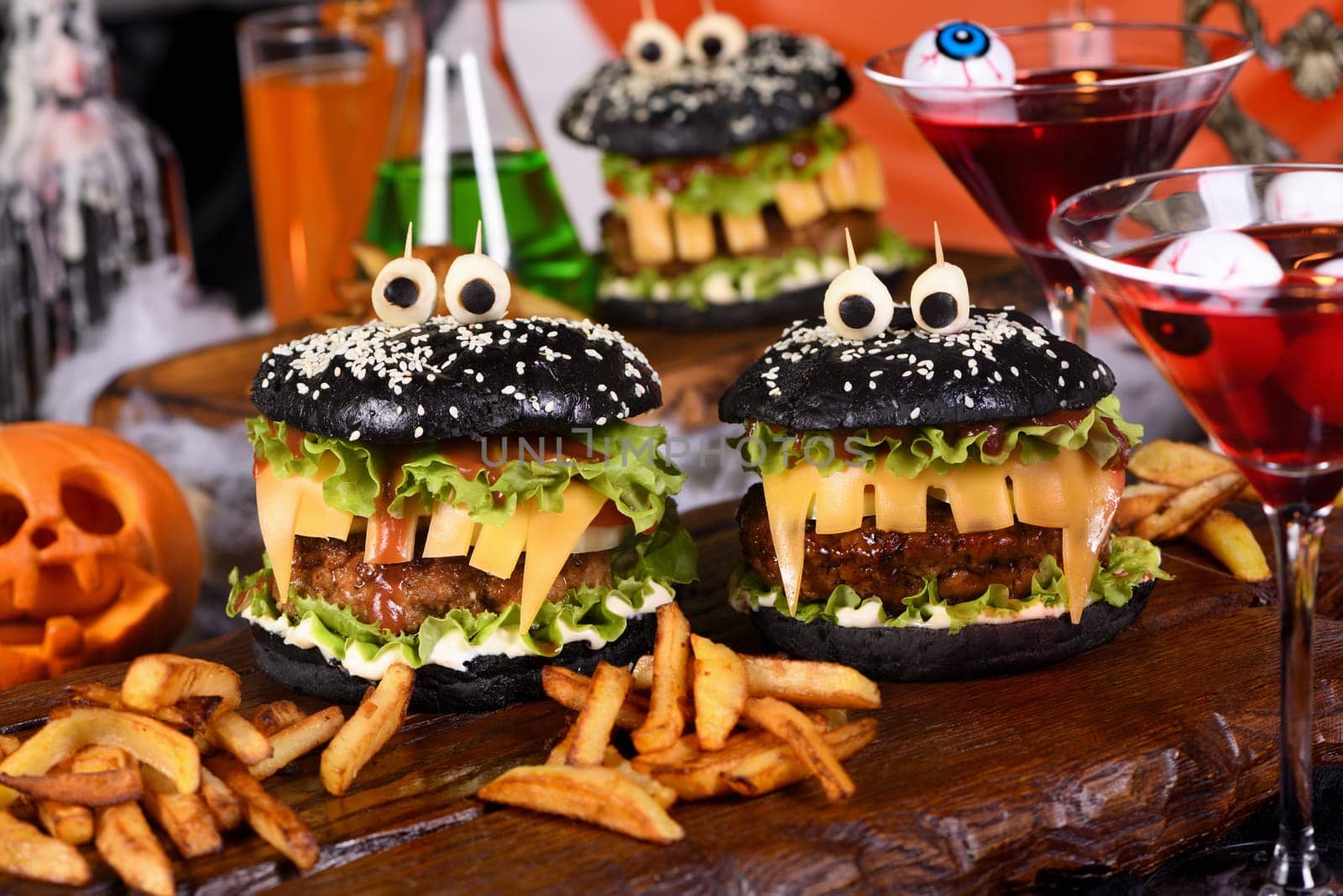 Monster Burger. Black bun, juicy beef cutlet, lettuce, onion, tomato and cheese in the shape of teeth, mozzarella eyes with olives. Definitely a pick-me-up and a perfect Halloween party appetizer.