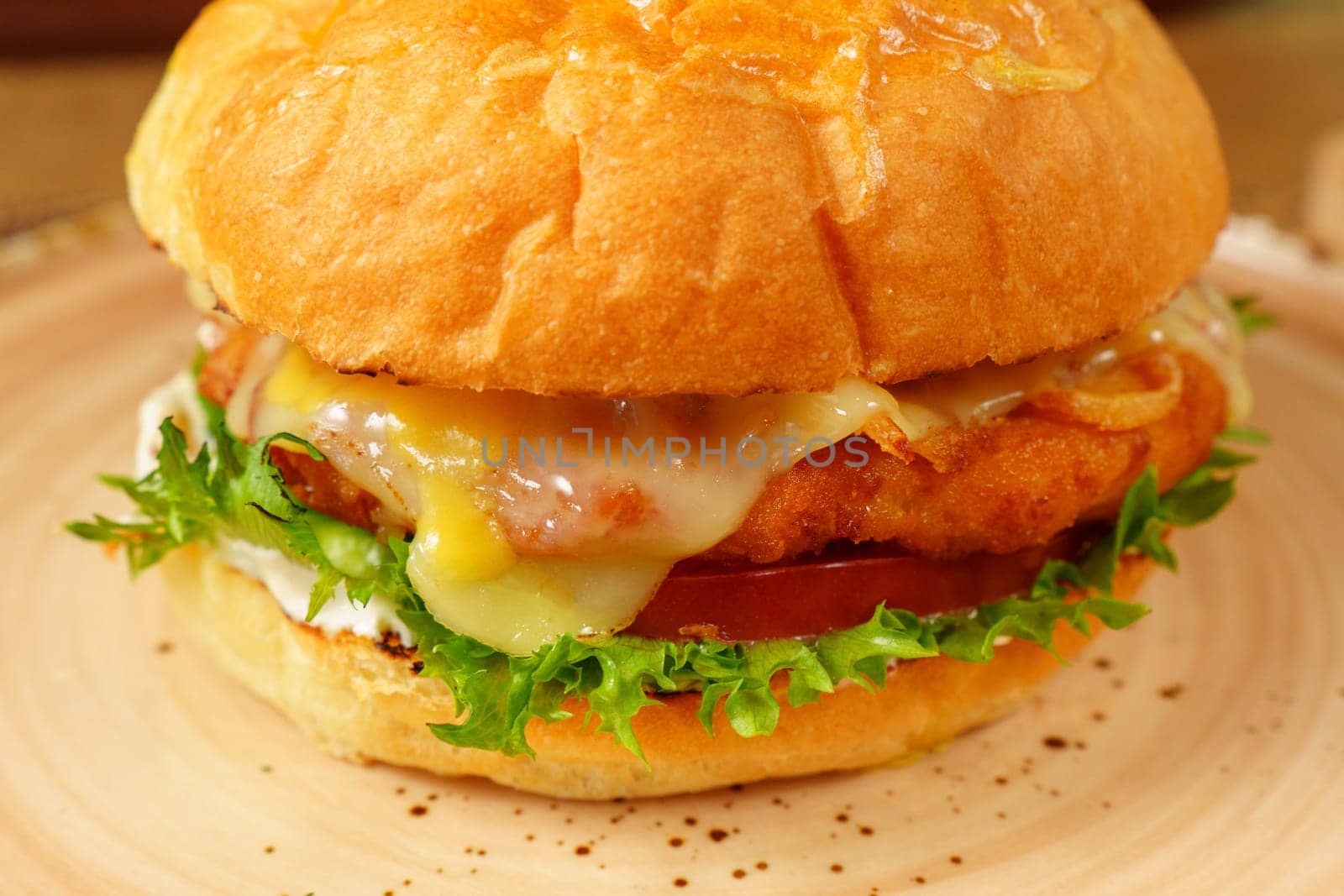 Cheeseburger topped with lettuce and various toppings placed on a plate, ready to be enjoyed.