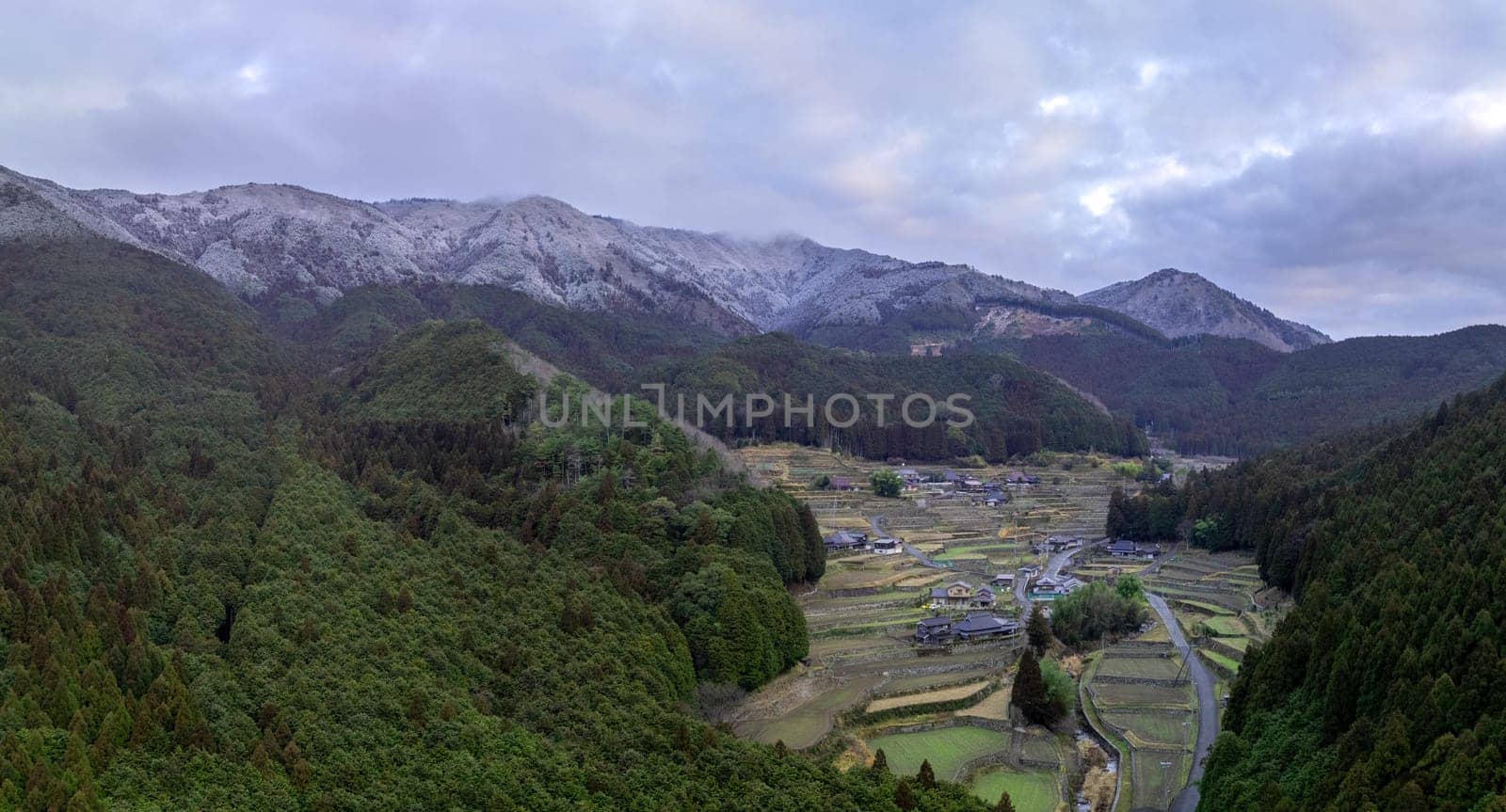 Terraced rice fields and snowy mountains in traditional Japanese village by Osaze