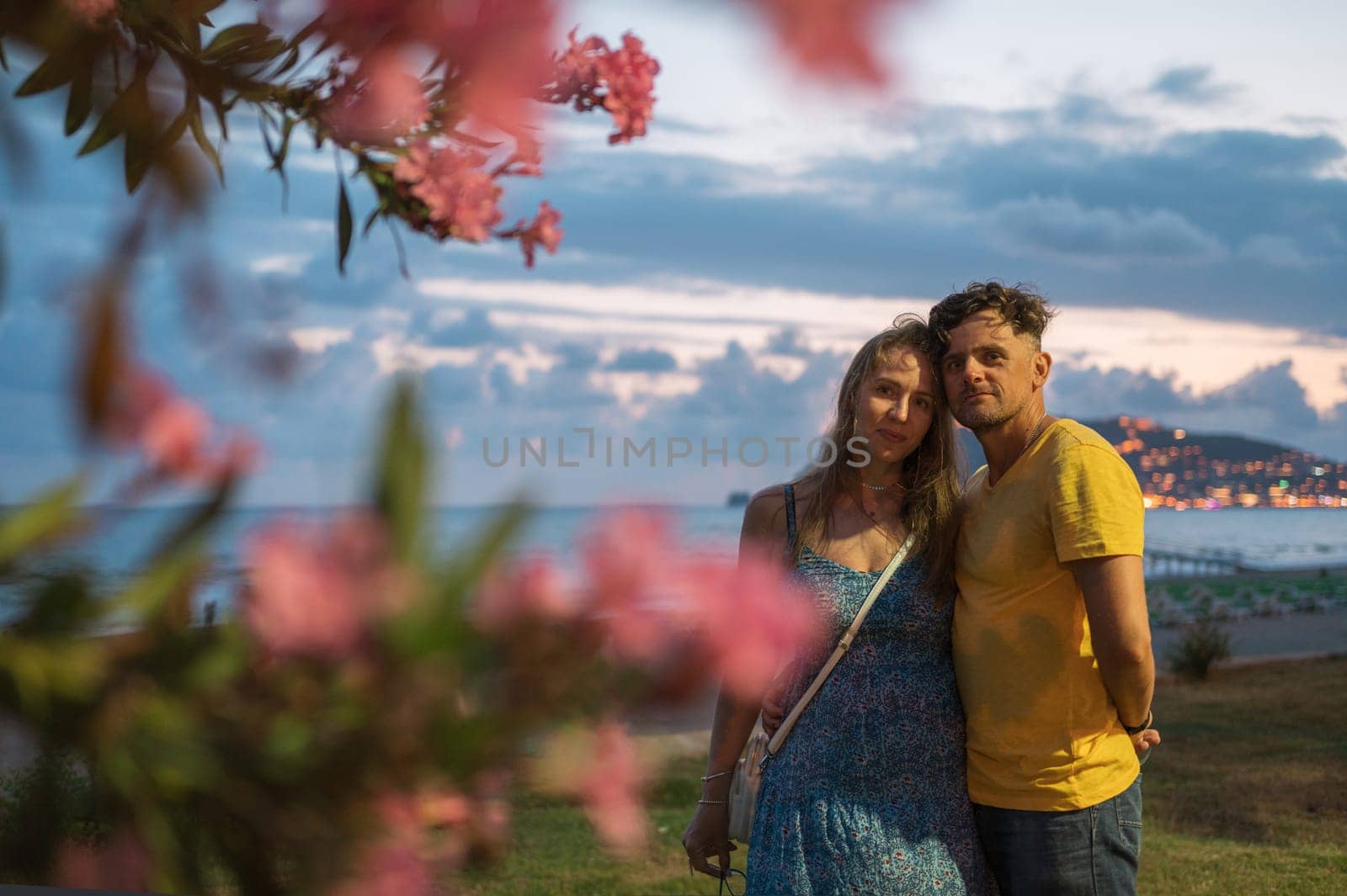 Happy couple taking a photo on a beach at the sea in Alanya city, Turkey. Focus on the background. Travelling or vacation concept