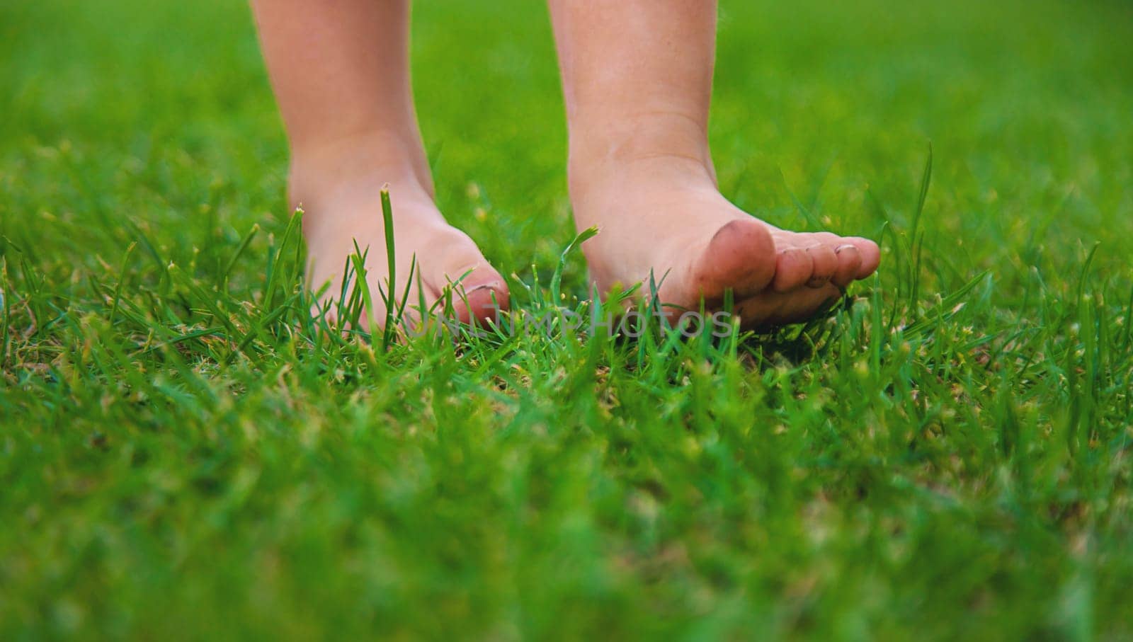 Child feet on the grass. Selective focus. by yanadjana