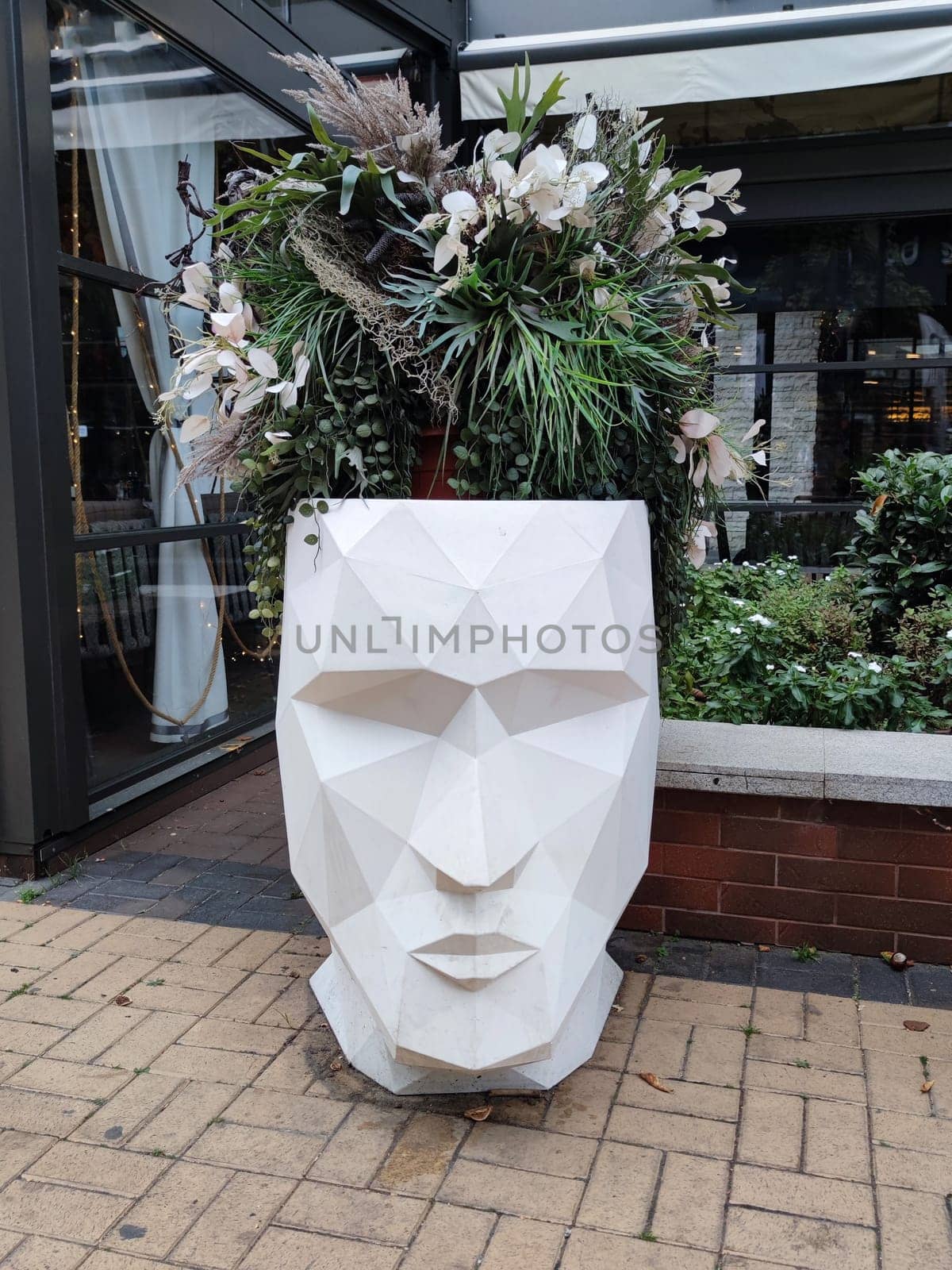 creative outdoor planter in the shape of a human head with flowers instead of hair.