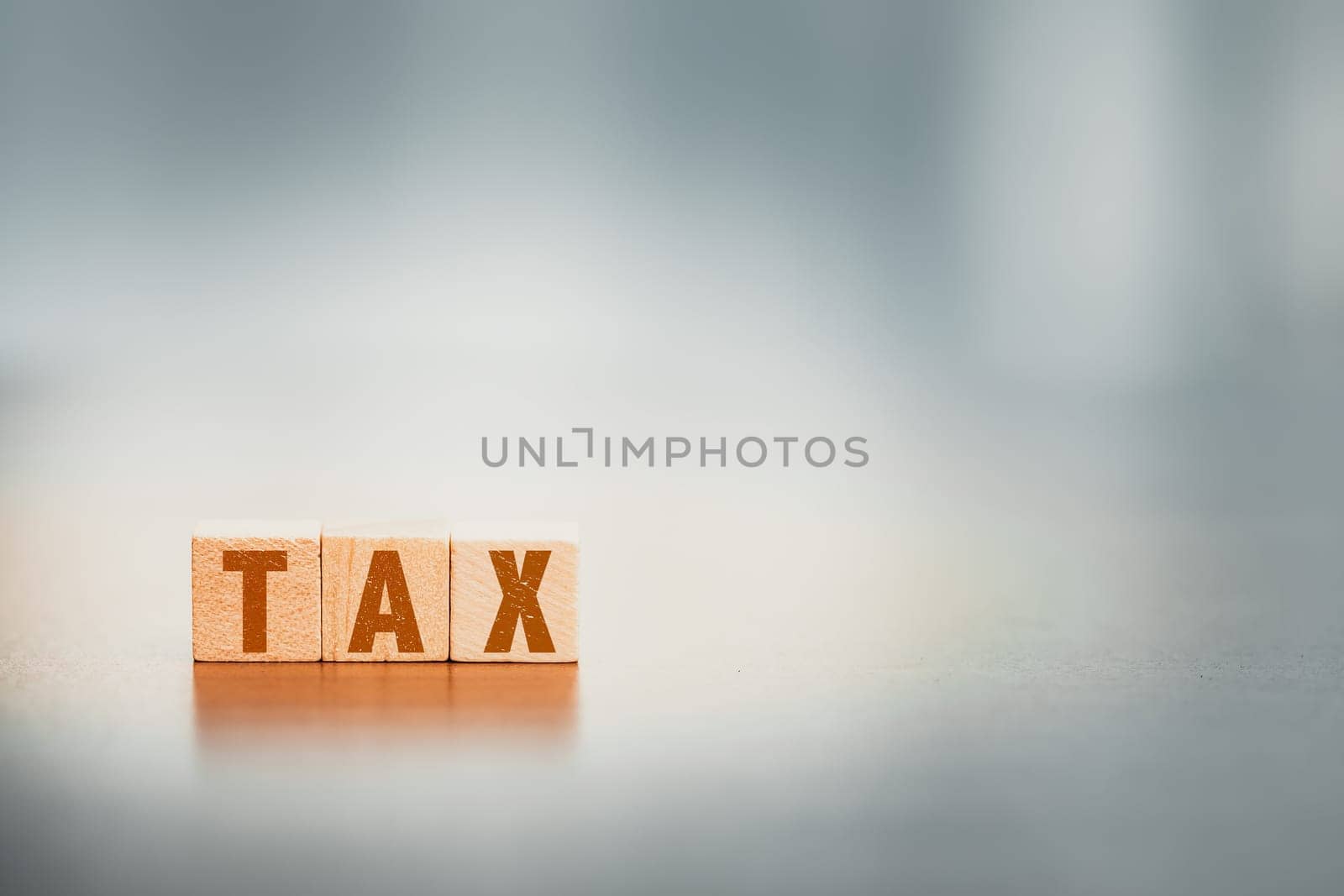 Wooden cubes with the word TAX on a desk, encapsulates a business concept related to financial responsibilities, accounting, and fiscal considerations.