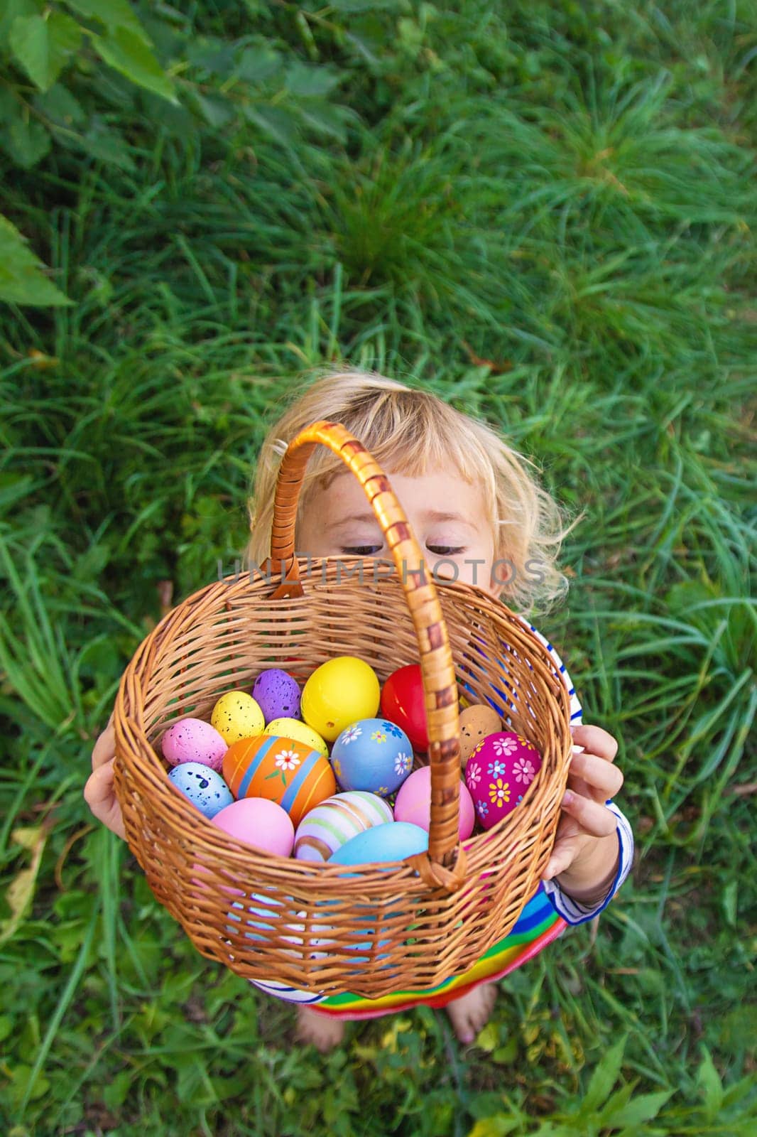 A child collects Easter eggs in the grass. Selective focus. by yanadjana