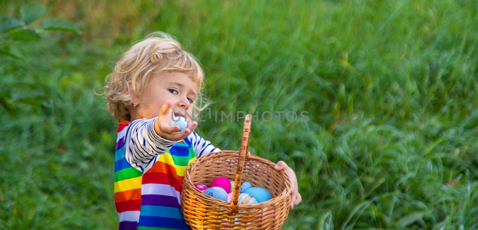 A child collects Easter eggs in the grass. Selective focus. by yanadjana