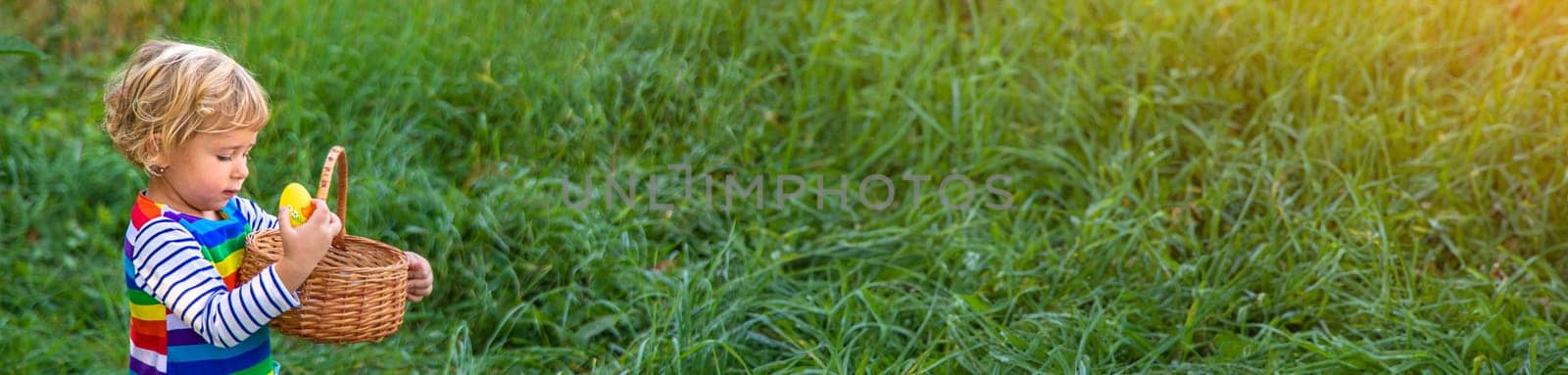 A child collects Easter eggs in the grass. Selective focus. by yanadjana