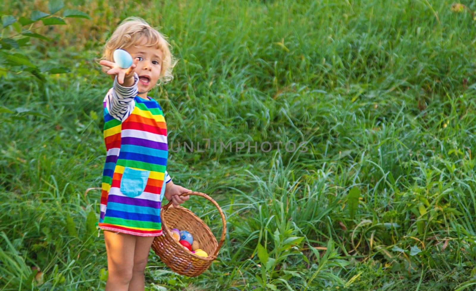 A child collects Easter eggs in the grass. Selective focus. by yanadjana