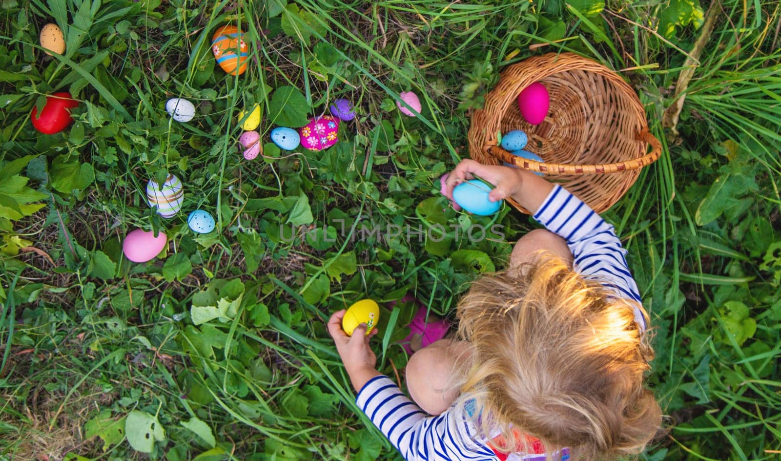 A child collects Easter eggs in the grass. Selective focus. Kid.