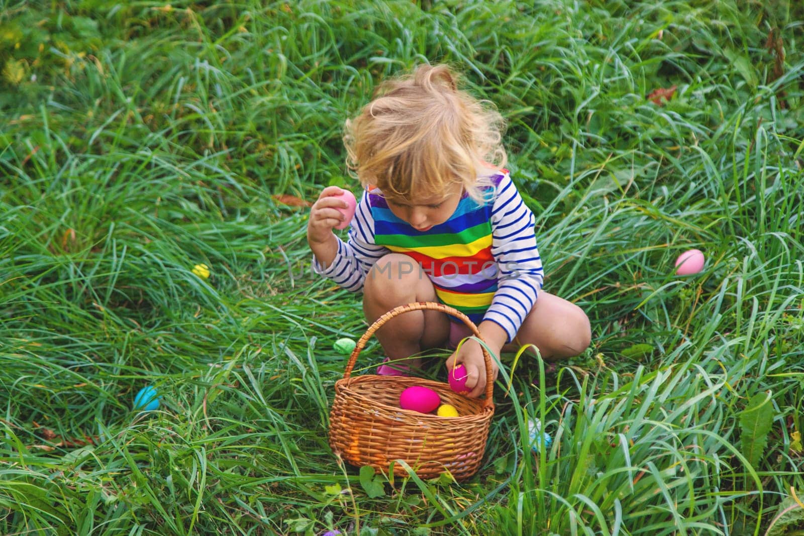 A child collects Easter eggs in the grass. Selective focus. Kid.
