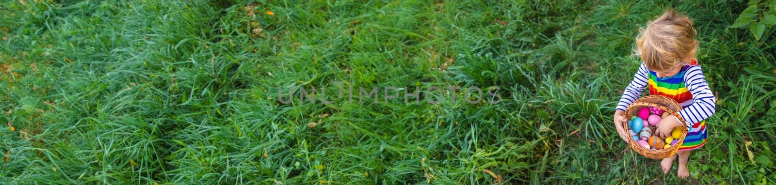 A child collects Easter eggs in the grass. Selective focus. Kid.