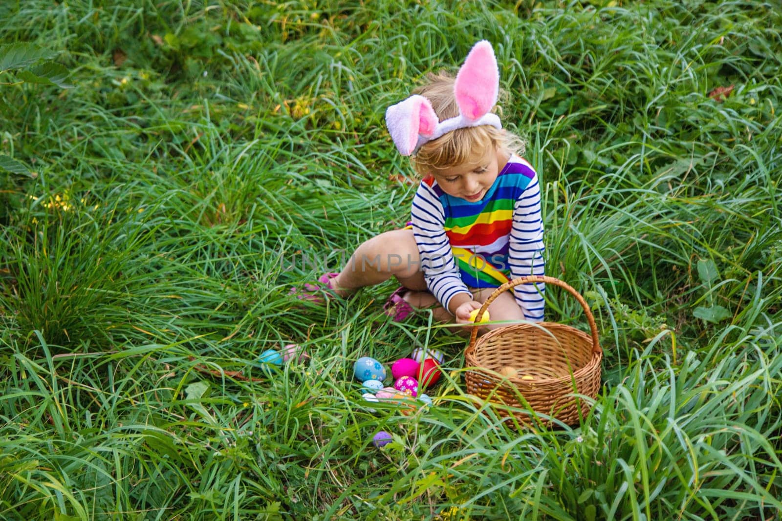 A child collects Easter eggs in the grass. Selective focus. by yanadjana